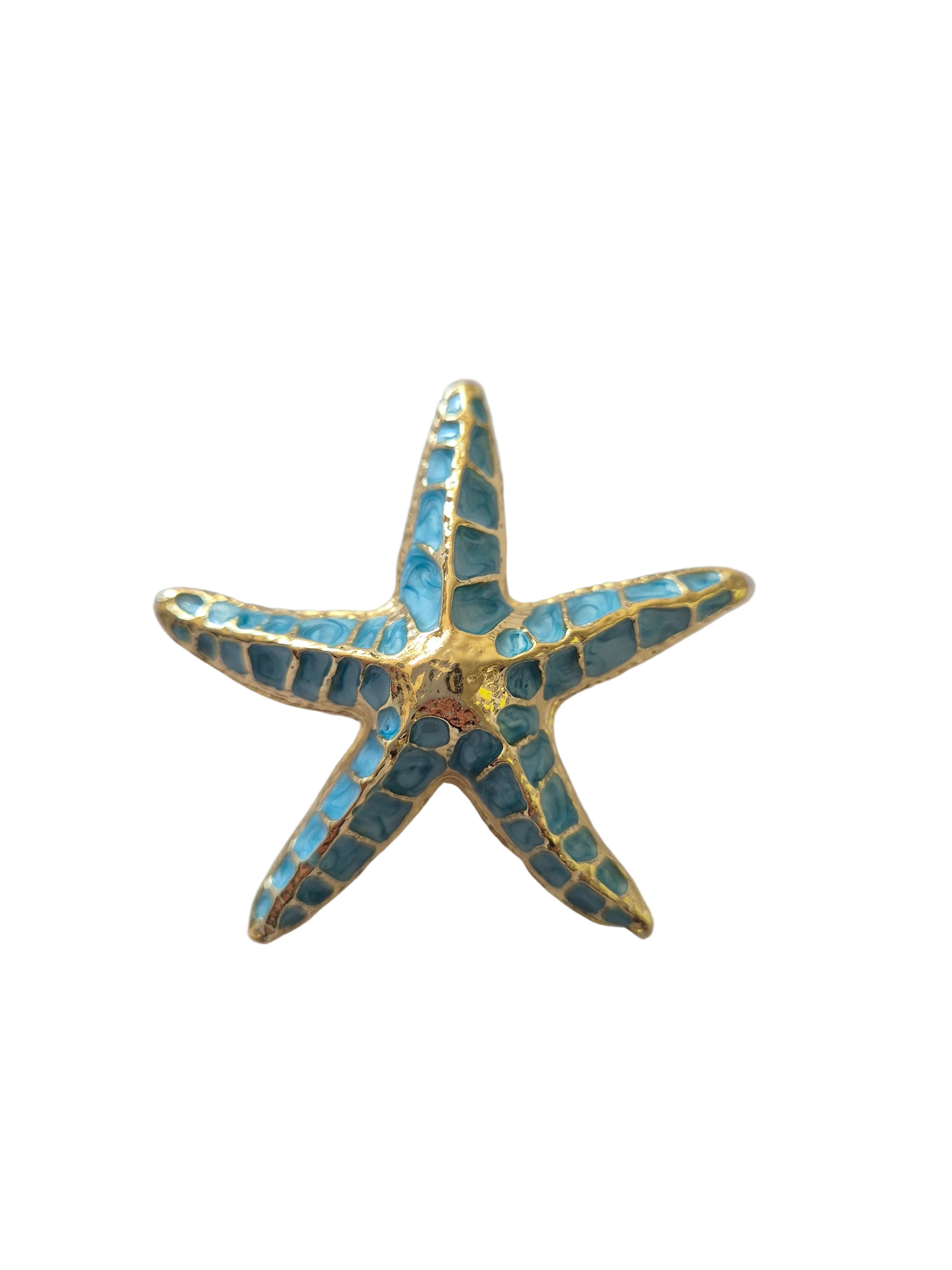 Starfish-shaped brooch with blue and gold design on a white background