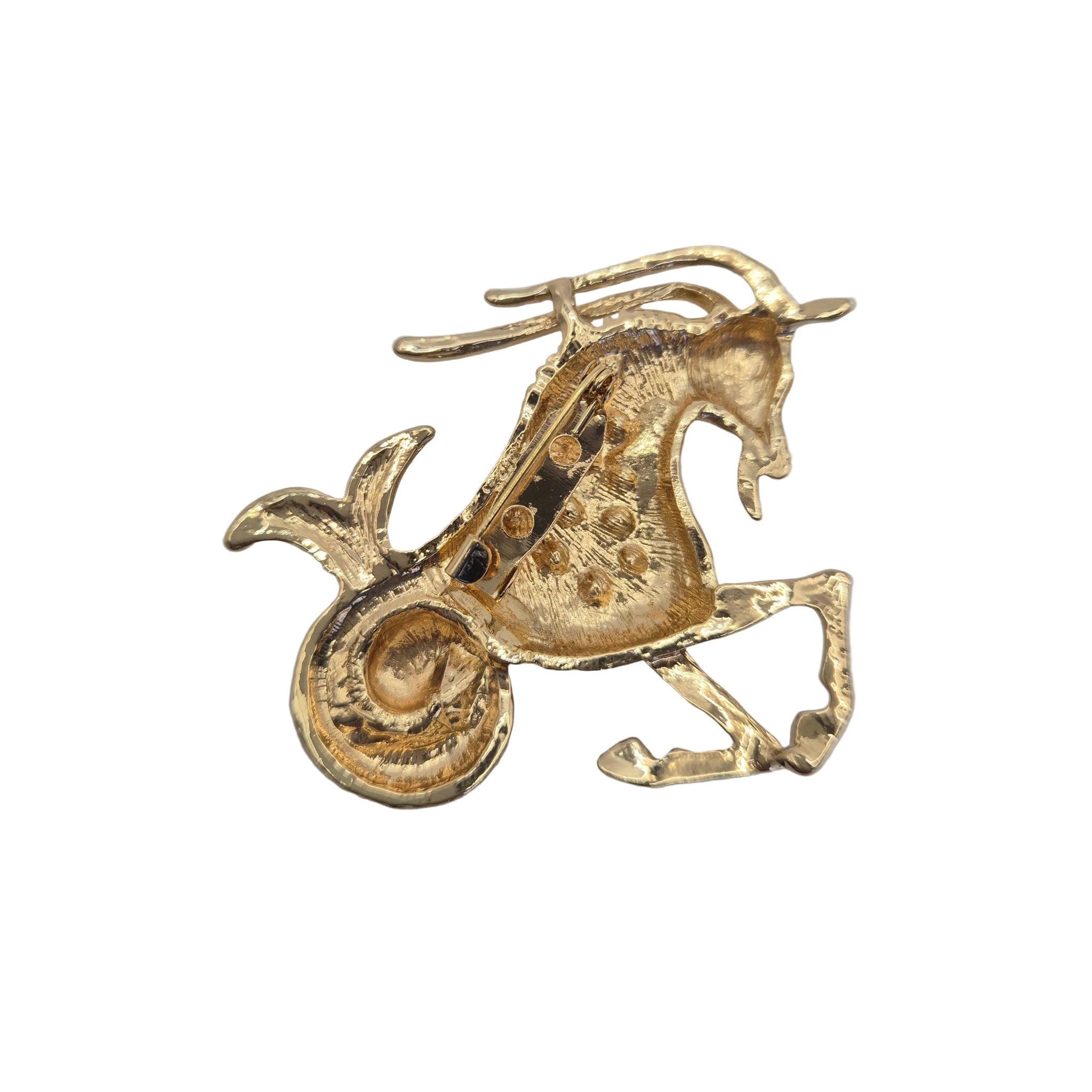 A small gold-toned capricorn zodiac shaped charm or pendant with a textured finish, photographed on a plain white background.