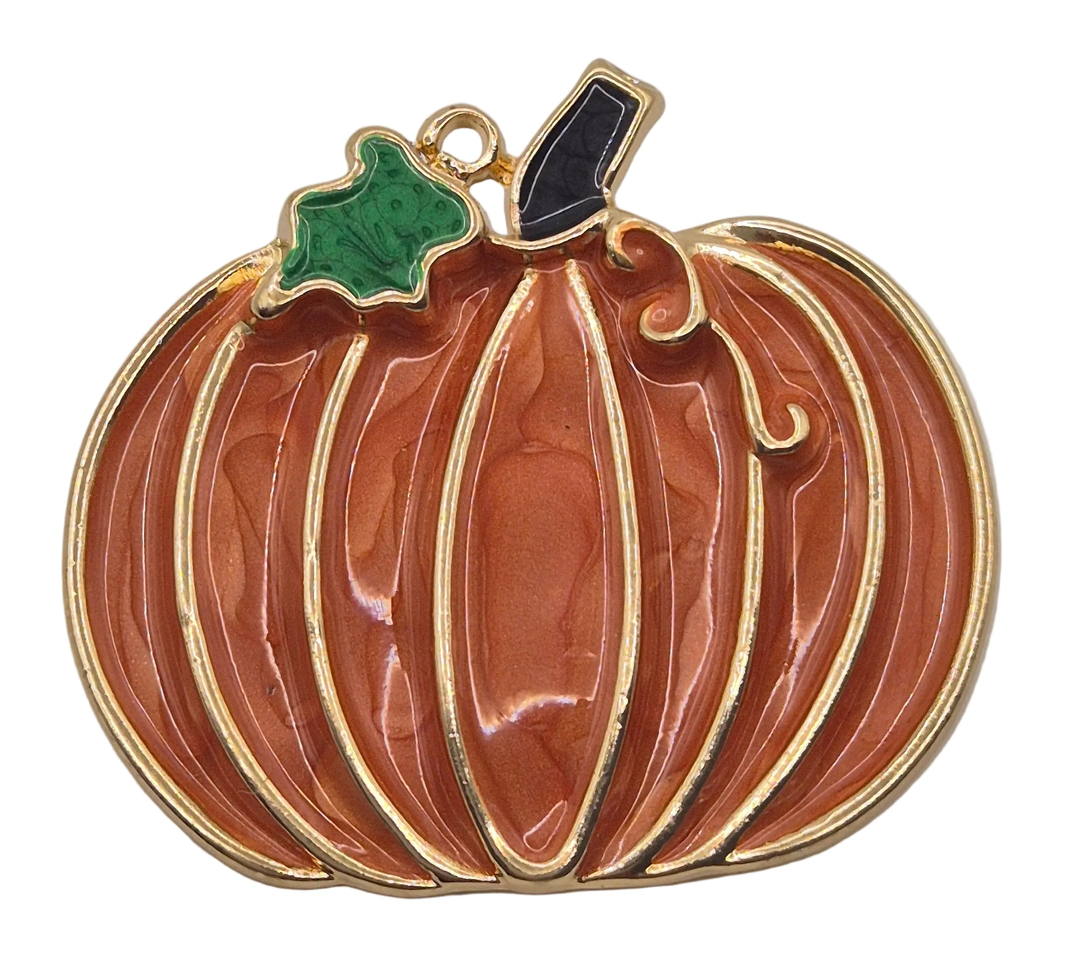 A pumpkin-shaped brooch with a glossy orange enamel body, gold-plated metal outlines, a green leaf-shaped accent, and a black stem, shown on a plain white background.