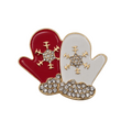 A pair of winter mitten-shaped brooch pins with one red mitten, one white mitten, gold-tone outlines, snowflake details, and rhinestone-embellished snow feet, displayed on a plain white background.