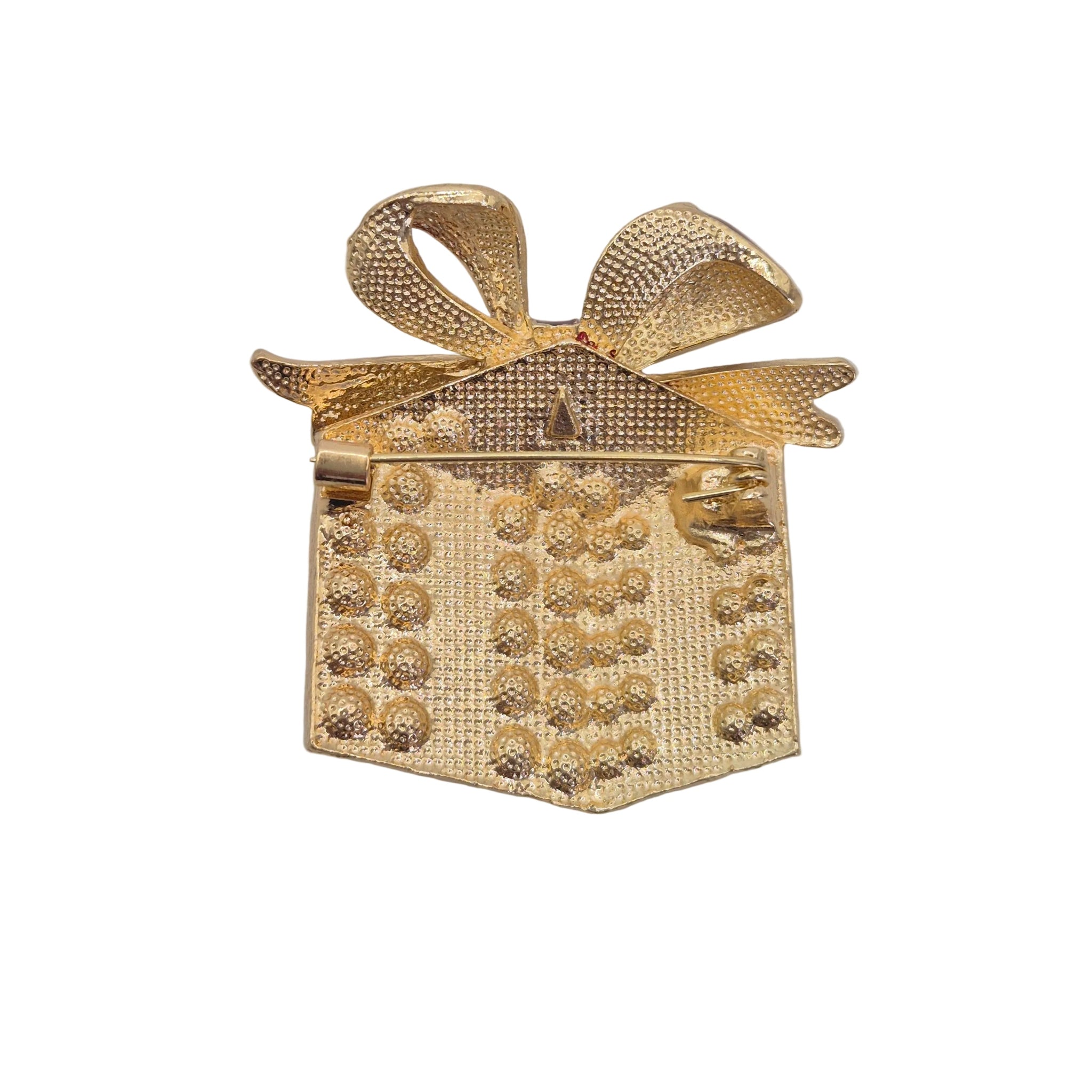A gold gift box brooch with a textured bow and embellished front, shown on a plain white background.