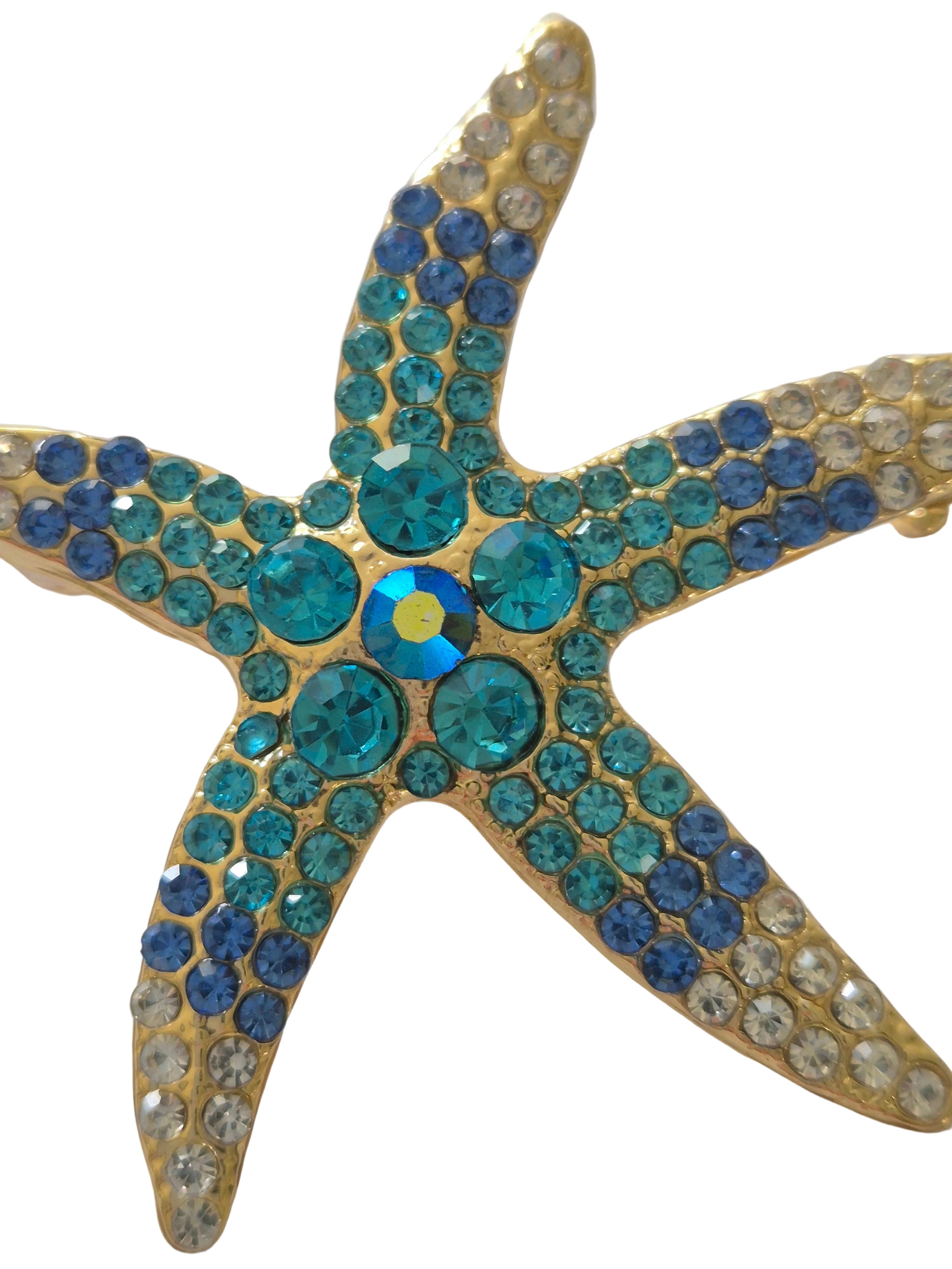 Starfish-shaped object with blue and gold gemstones on a white background