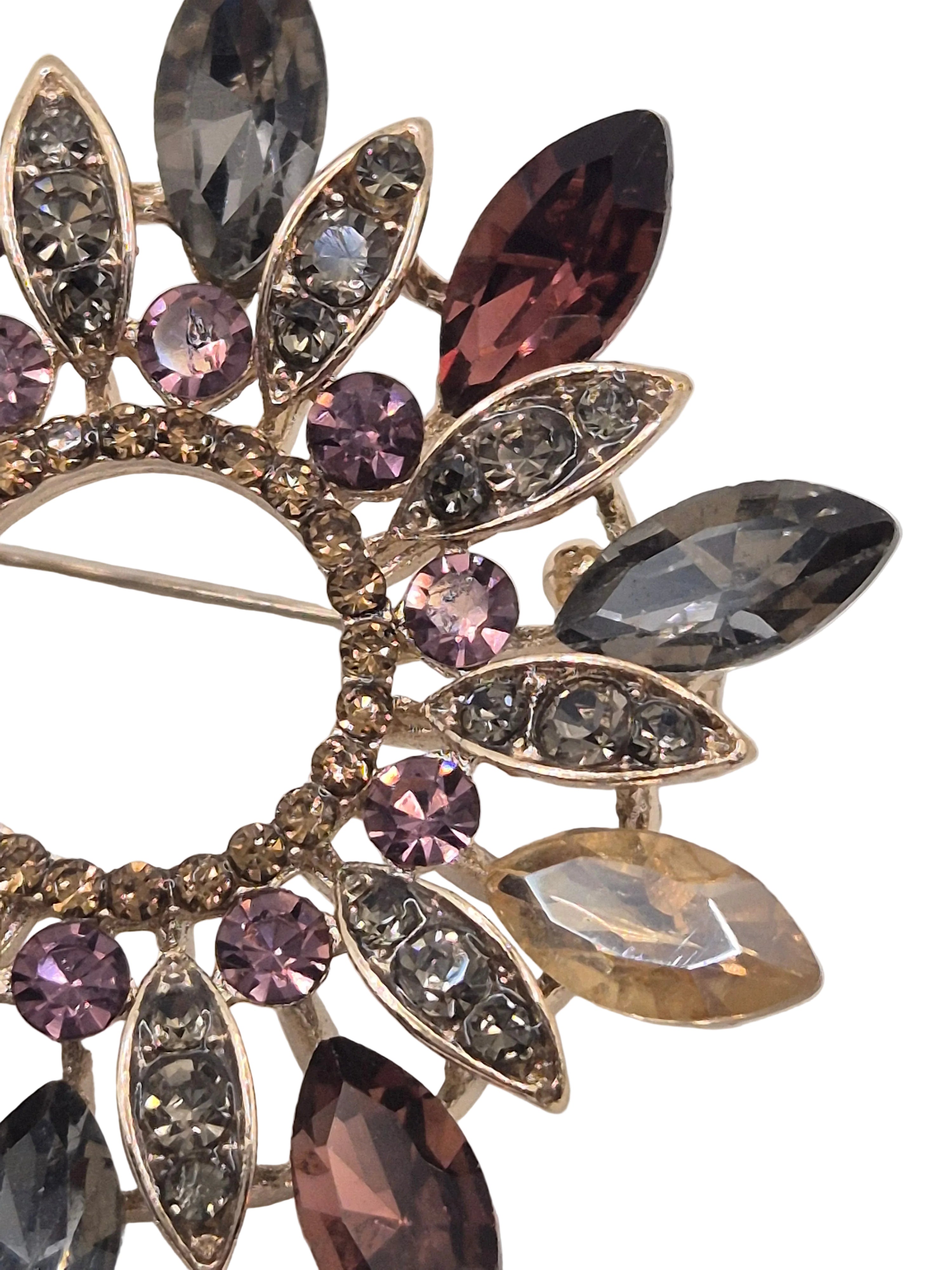 Decorative wreath brooch with multicolored gemstones on a white background