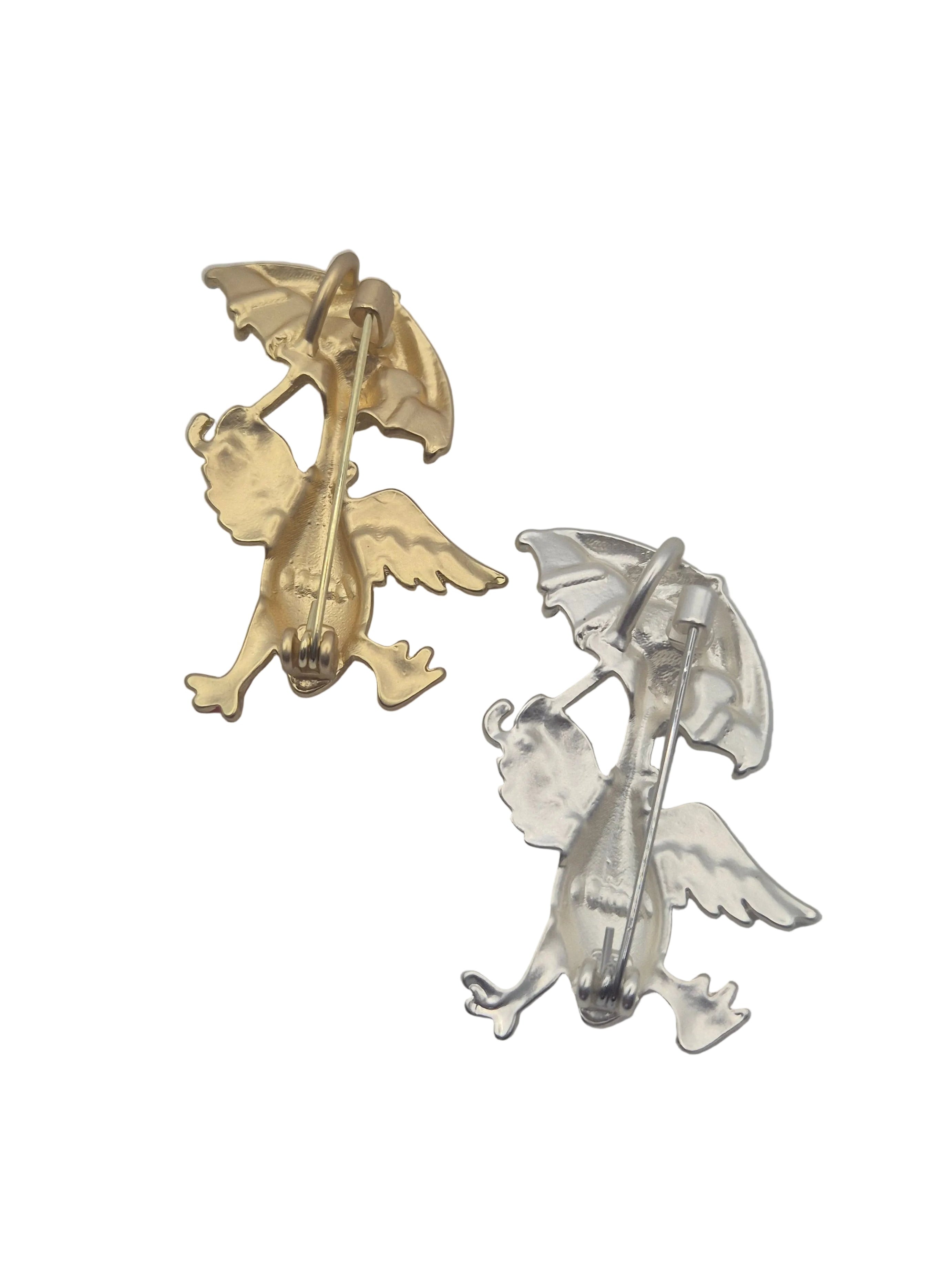 Two duck brooches in gold and silver tone metal on a plain white background 