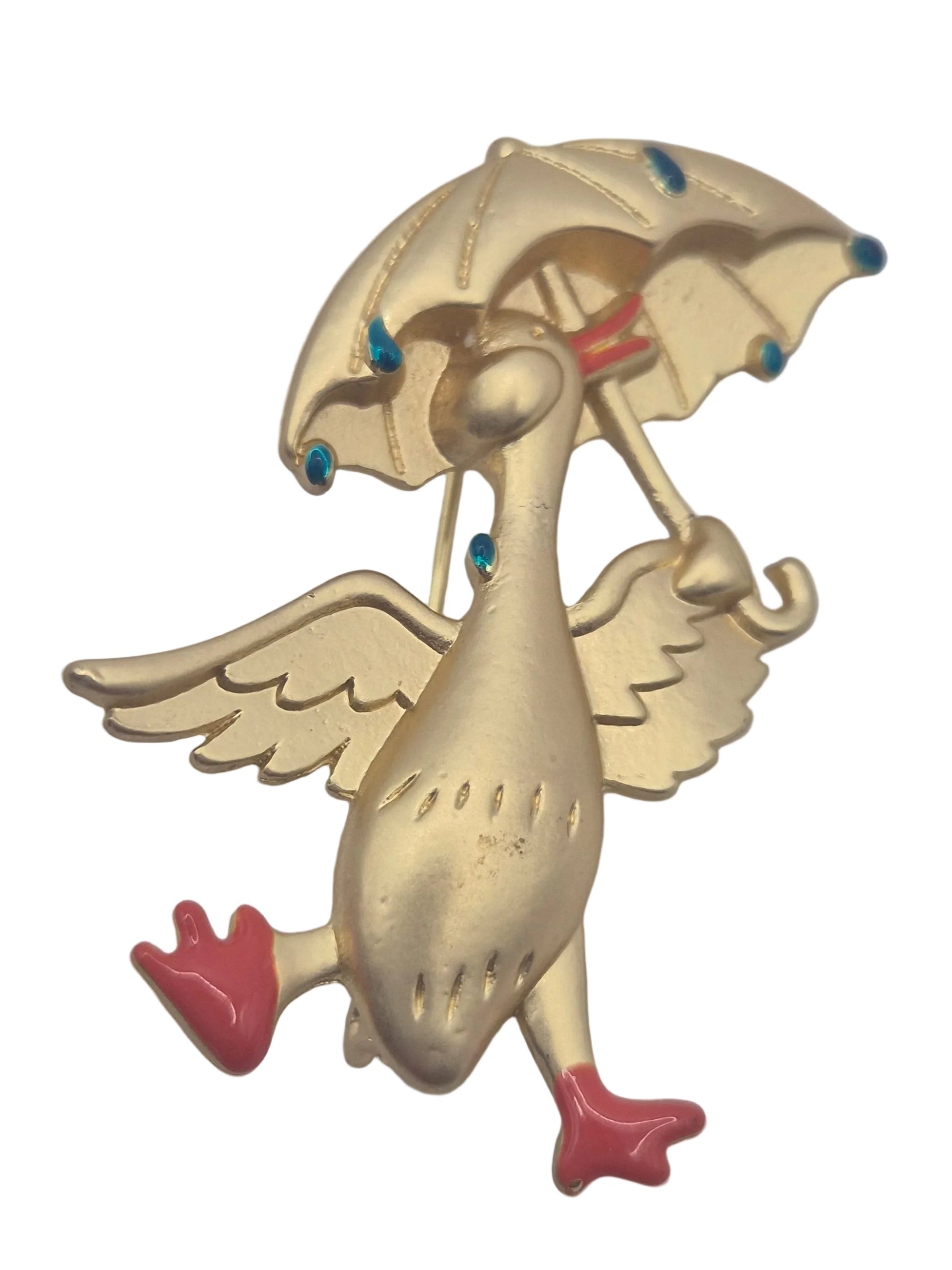 Gold tone metal duck holding an umbrella brooch with raindrops on a plain white background 