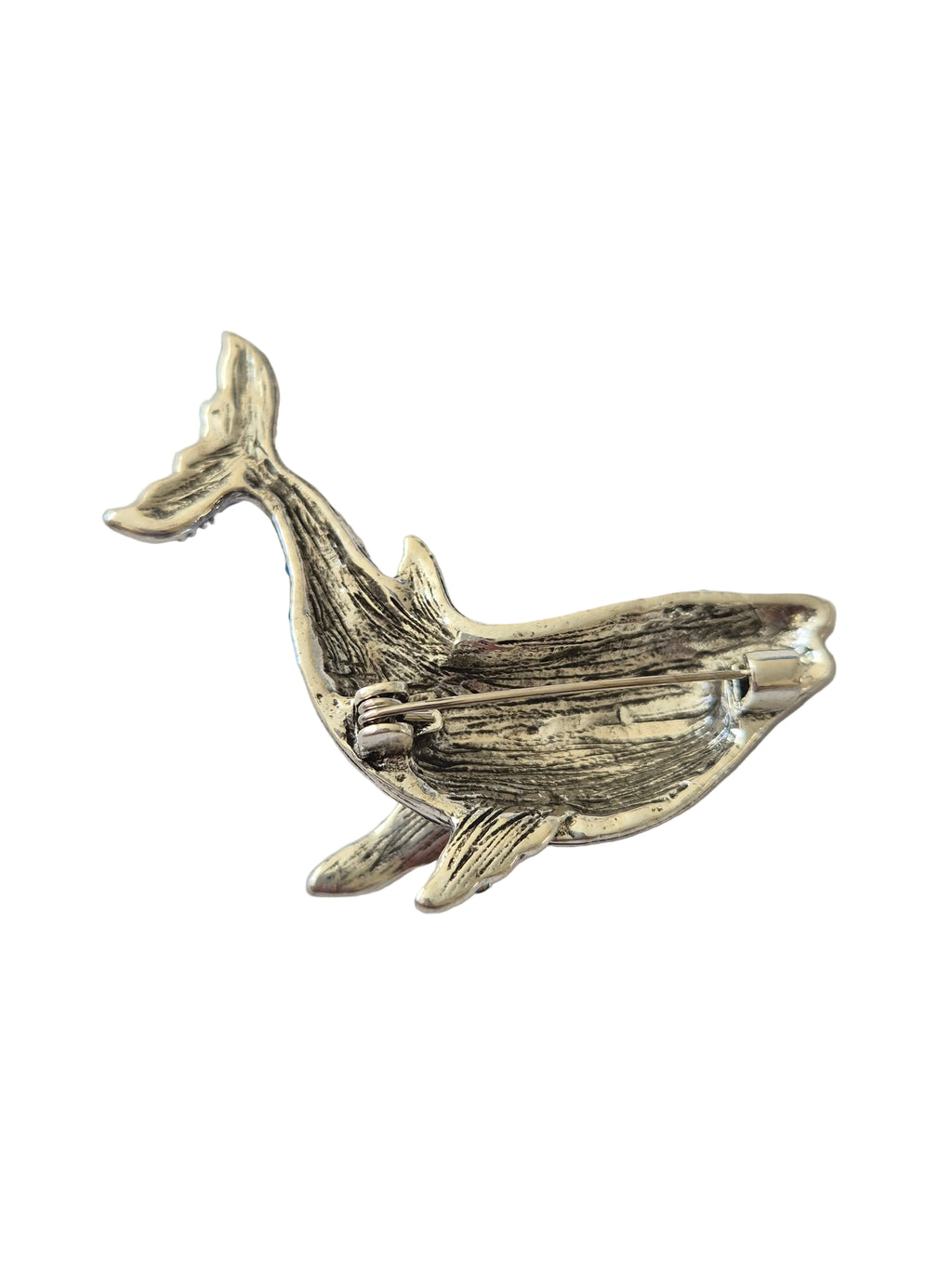Blue rhinestone whale brooch on plain background