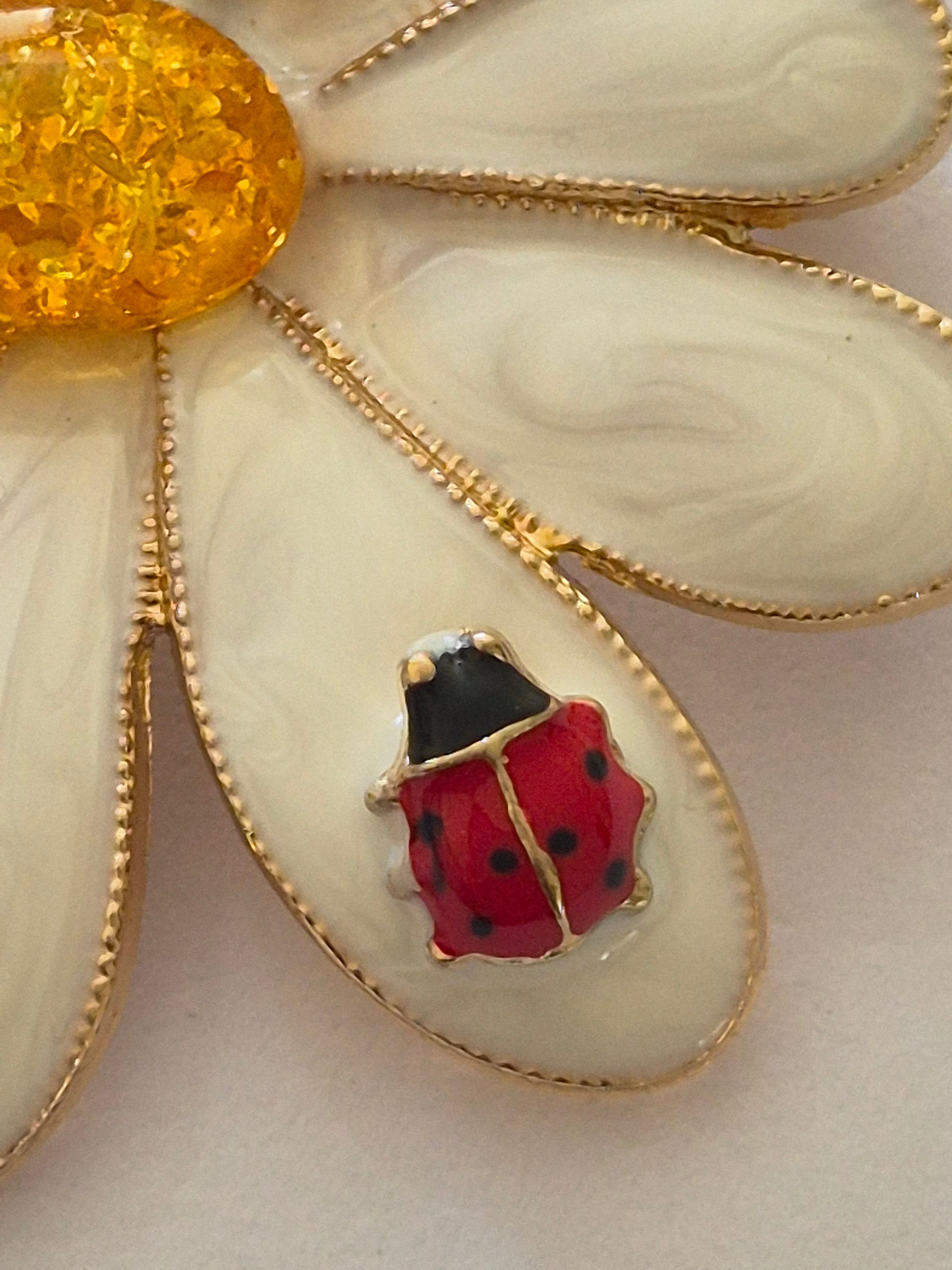 Daisy brooch with a ladybird detail on a white background