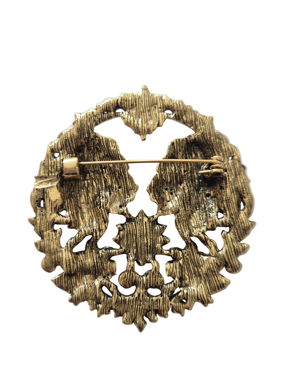 gold brooch with intricate design on a white background