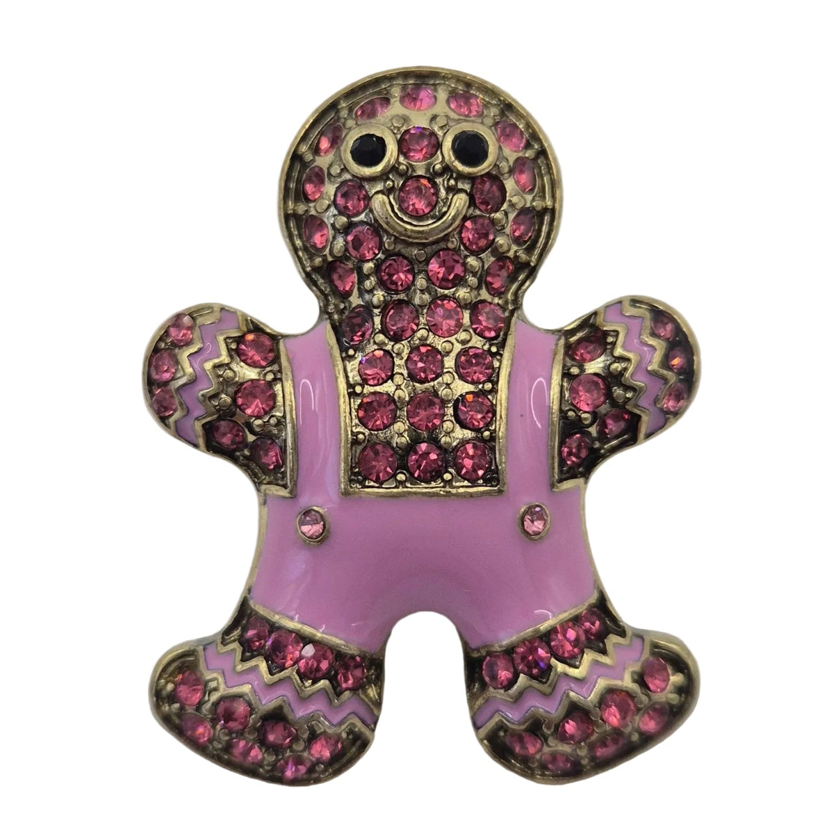 A small gingerbread person-shaped earring with a pink and black patterned body, gold-toned outlines, and a light pink overalls-style section, photographed on a plain white background.