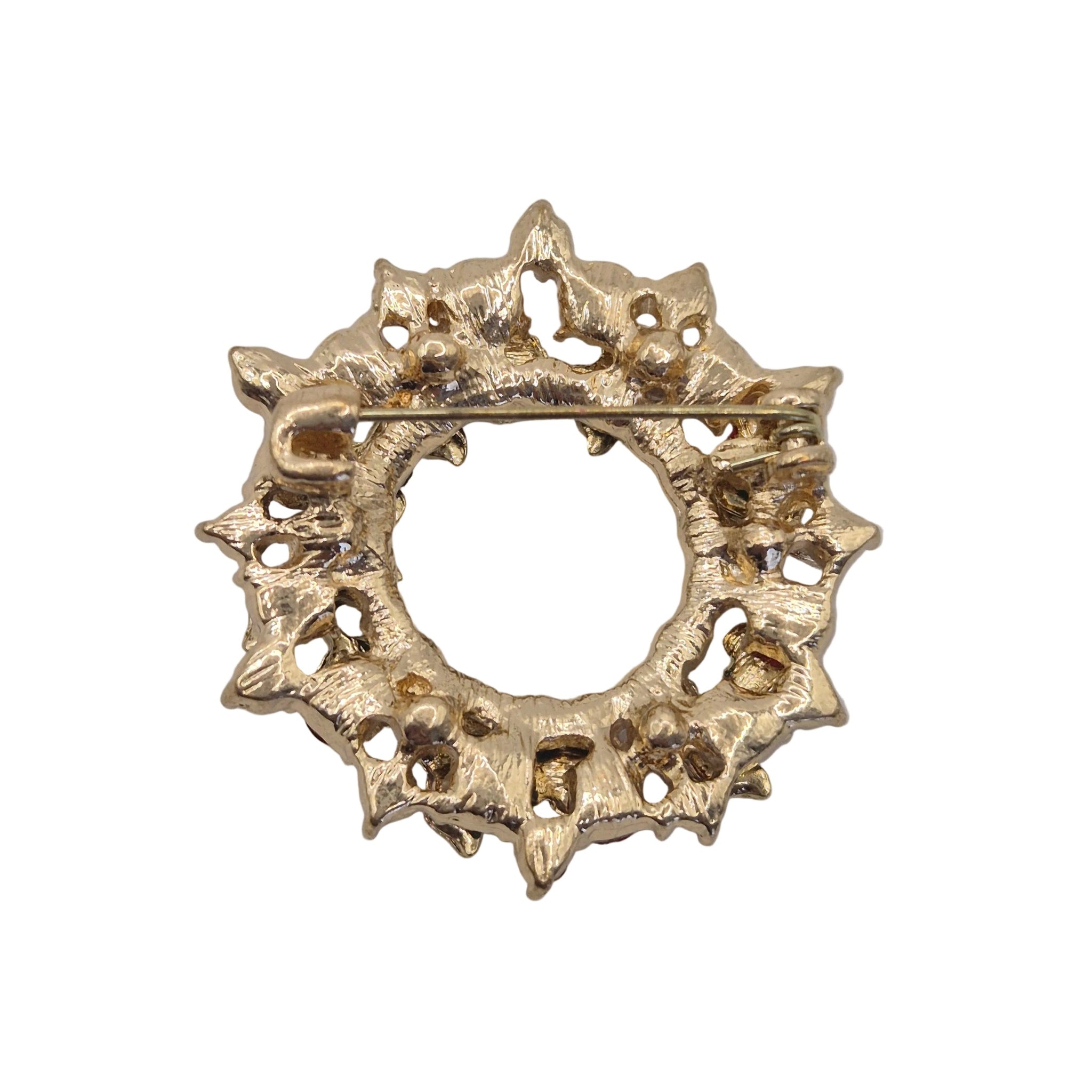 A gold-tone circular wreatg brooch with a textured, starburst-like floral pattern and a pin clasp across the top, shown on a plain white background.