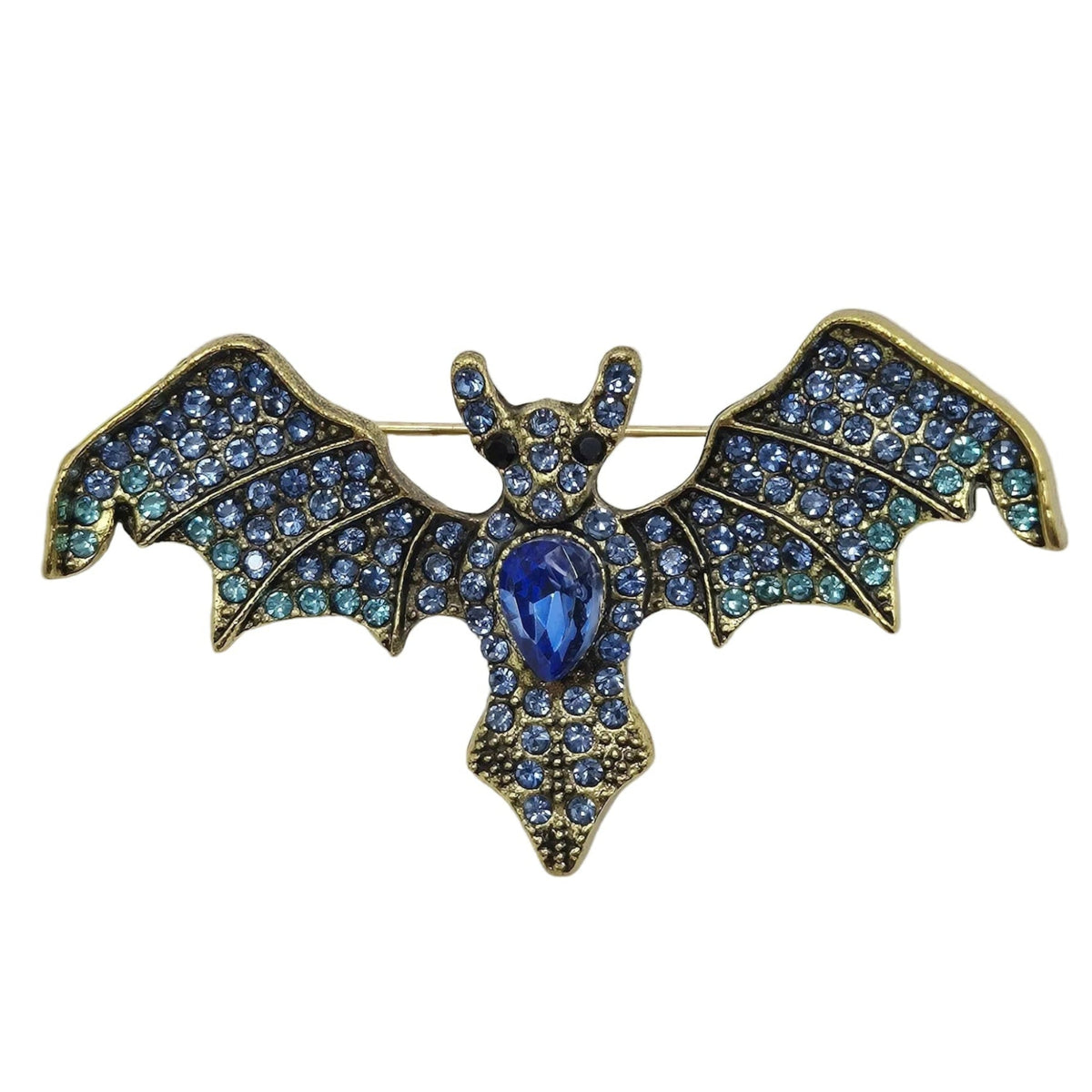 A vintage-style bat brooch featuring blue rhinestones on its wings and a central blue stone, set in gold-toned metal, photographed against a plain white background.
