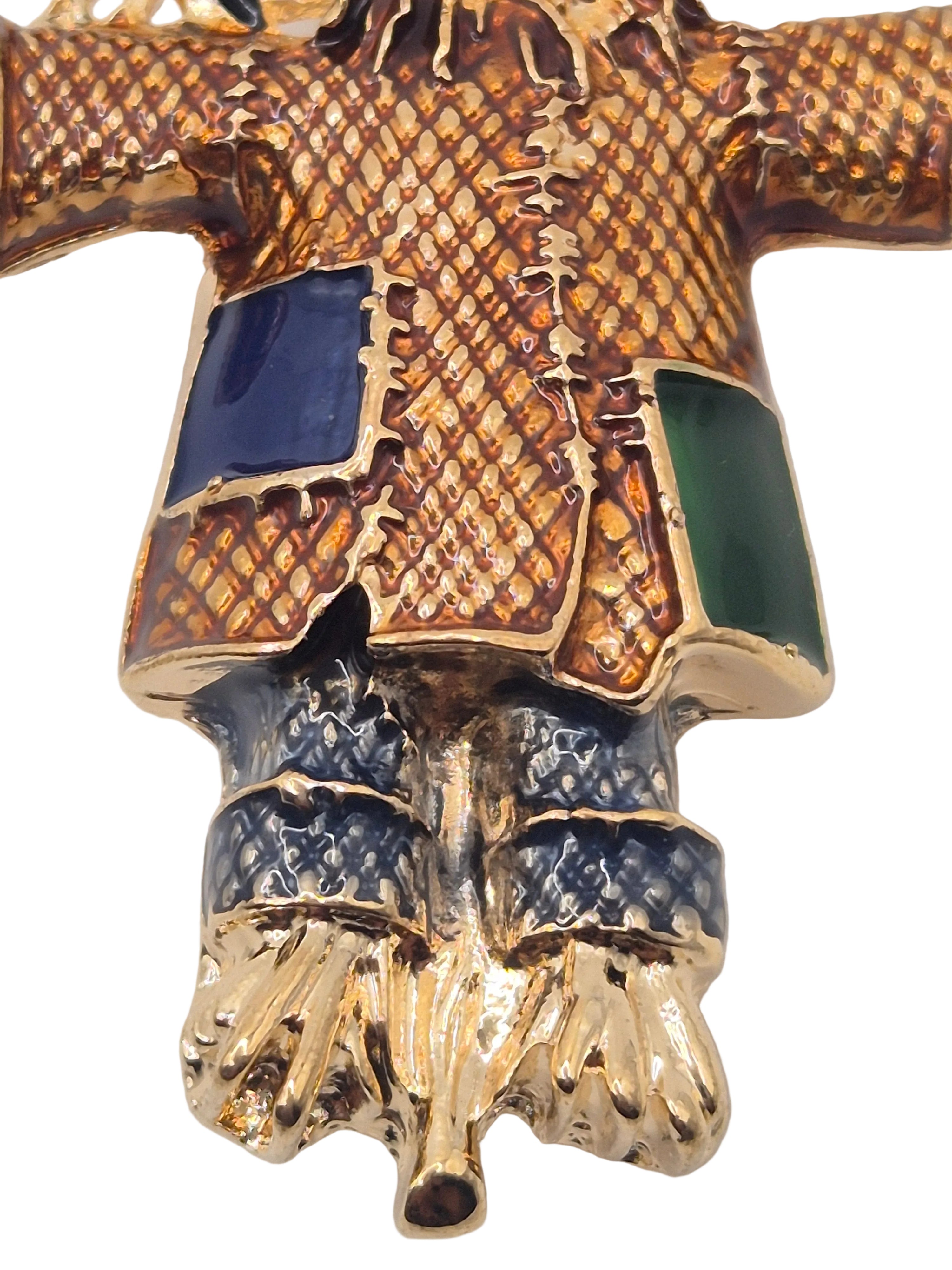 scarecrow brooch with blue and green stones on a white background
