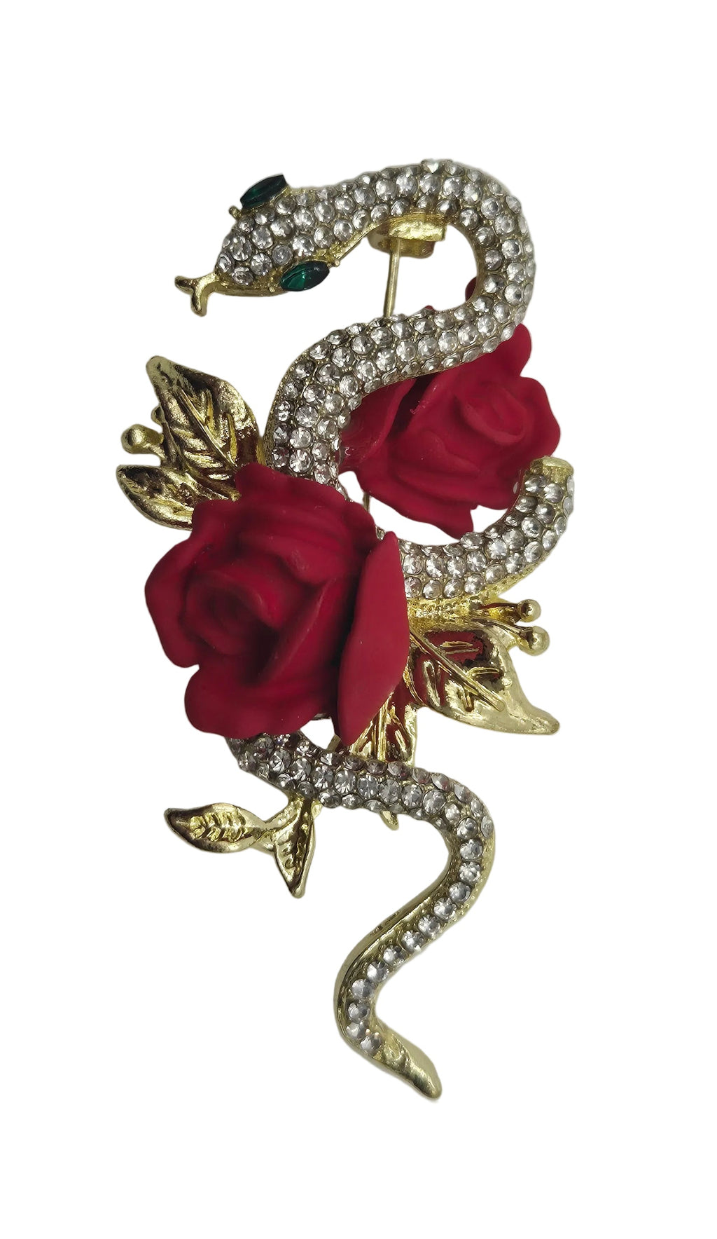 A gold metal snake brooch encrusted with clear rhinestones, featuring two red fabric roses and green gemstone eyes, set against a plain white background.