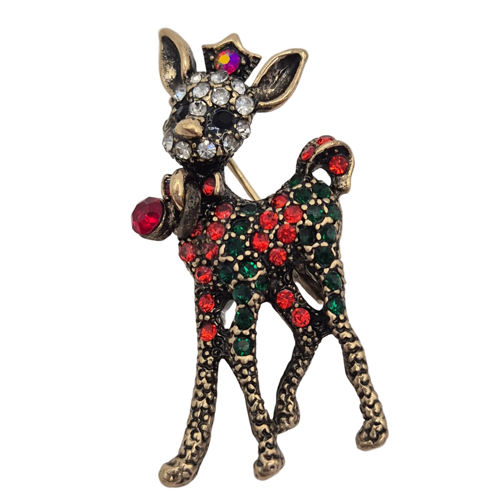 A Christmas-themed deer brooch featuring an antique gold-tone finish, adorned with red and green rhinestones on its body, a red bell, and a multicolor star on its head, set against a plain white background.