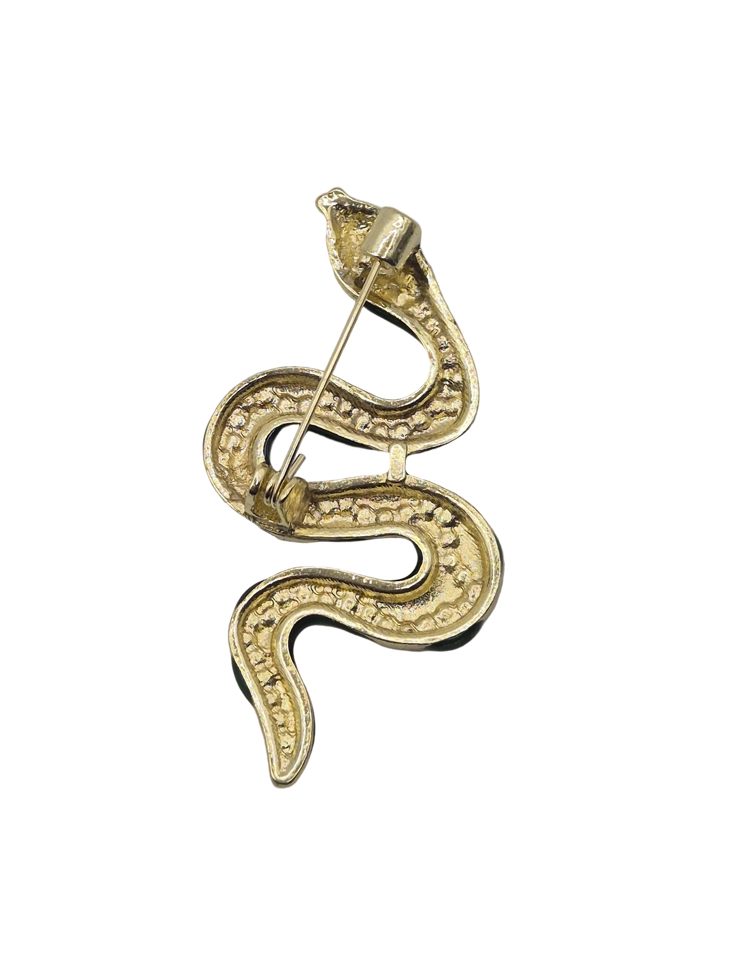 A gold snake-shaped brooch with a textured pattern and a pin clasp, shown on a plain white background.