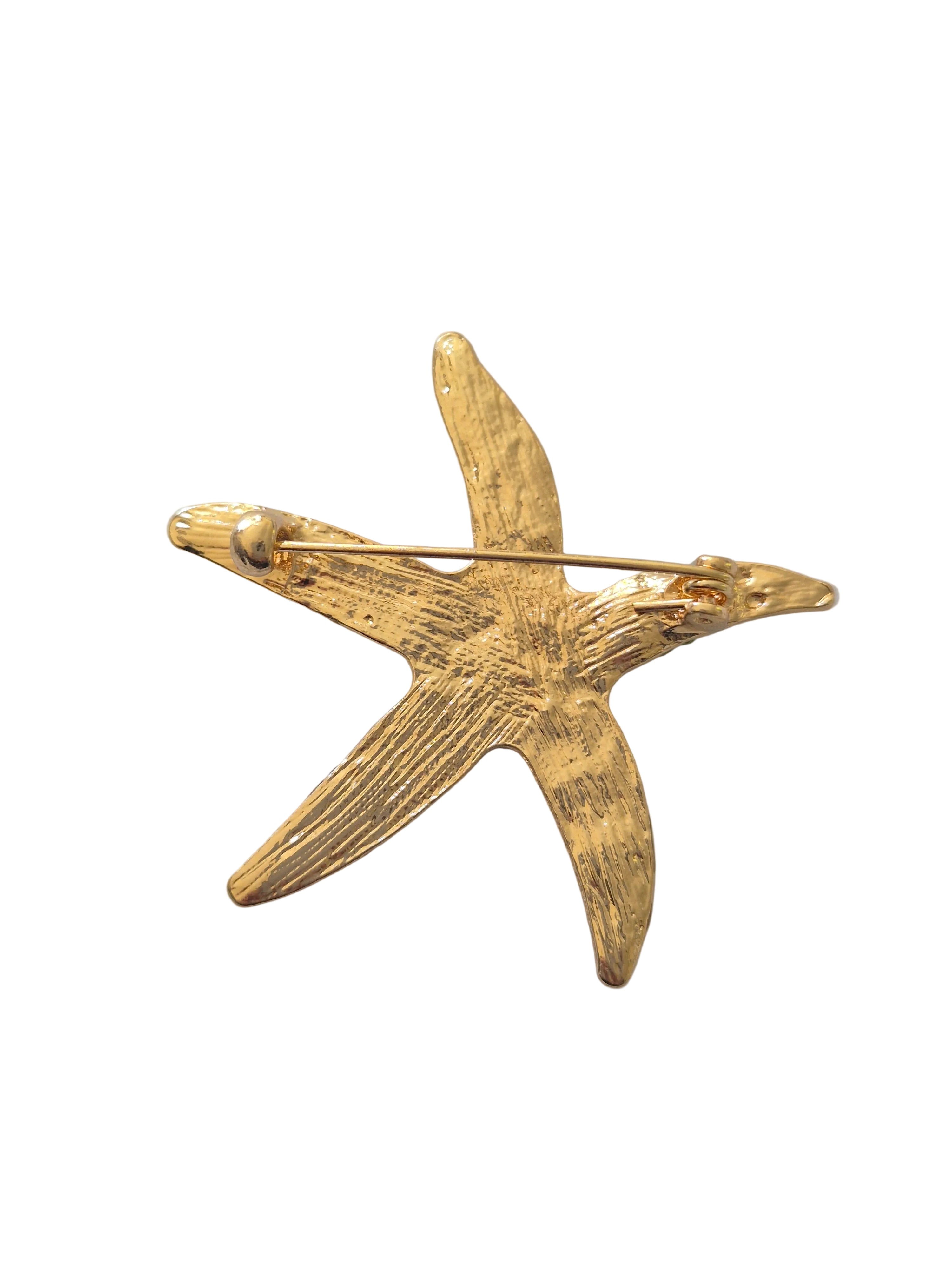 Gold starfish-shaped brooch on a white background