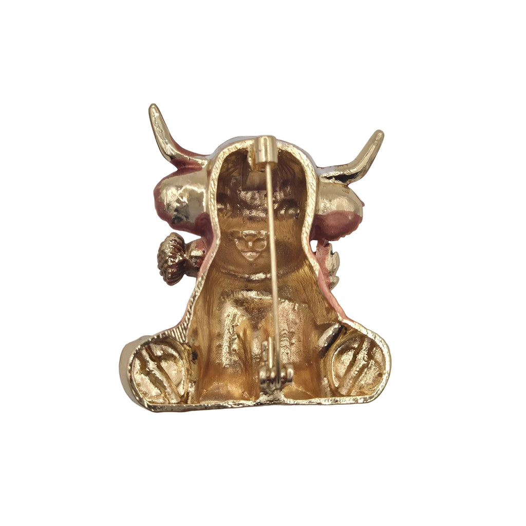 A highland cow brooch with long horns, shown on the reverse side with pin mechanism on a plain white background.