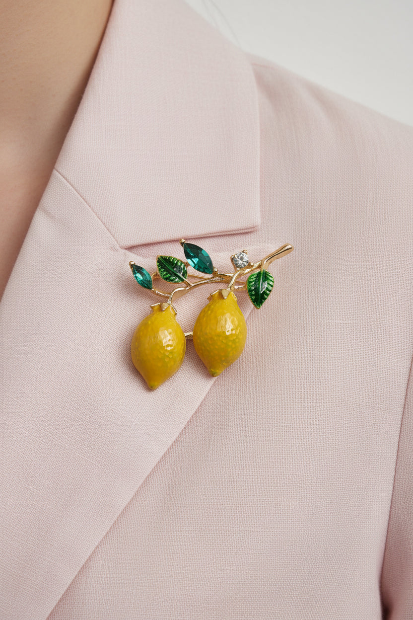 two yellow lemons brooch and green leaves on a gray background