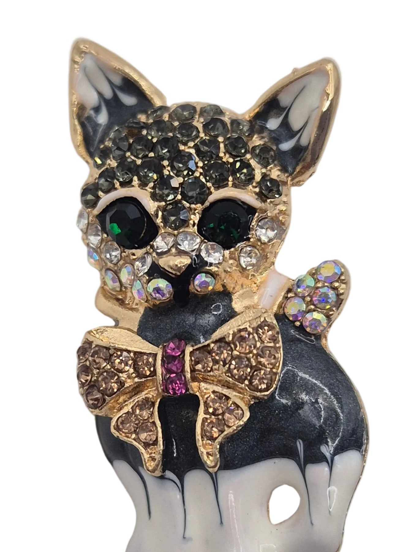 A decorative cat-shaped brooch or pin with gold-tone metal, black and white enamel, rhinestone-covered details, and a bow motif on a plain white background.