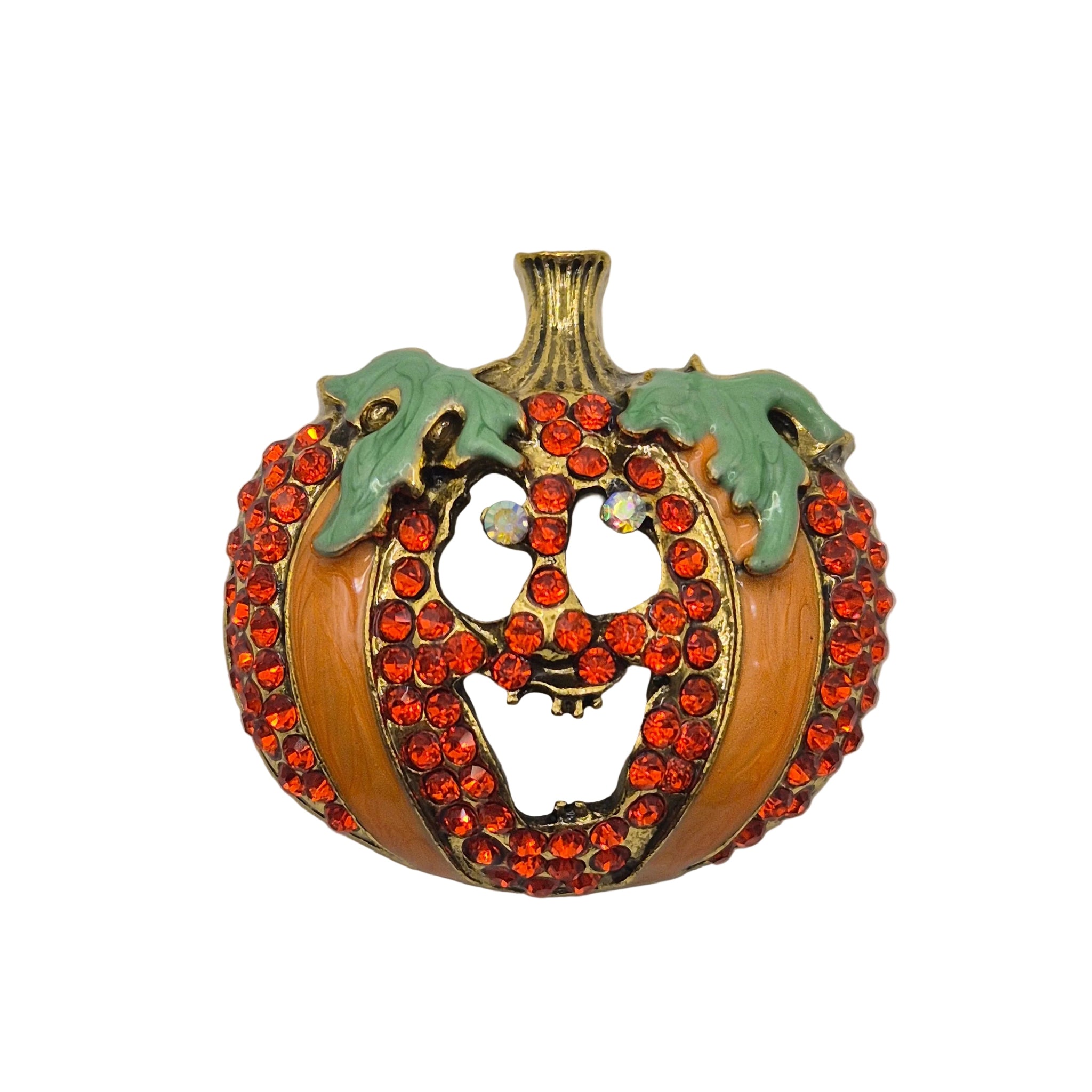 A vintage pumpkin-shaped brooch featuring a gold-tone metal base, decorated with rows of orange-red rhinestones and two light green enamel leaves on a plain light gray background.