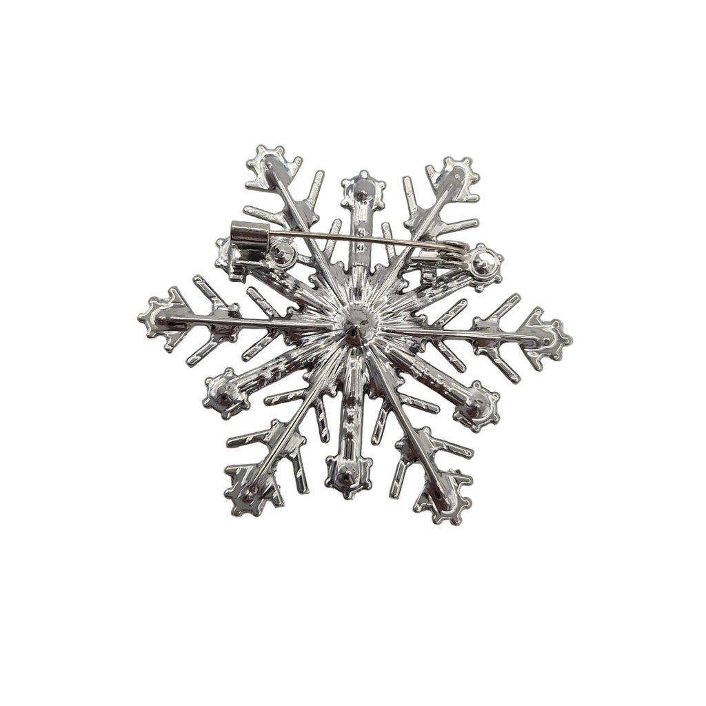 A silver snowflake-shaped brooch with a pin back, displayed on a white background.