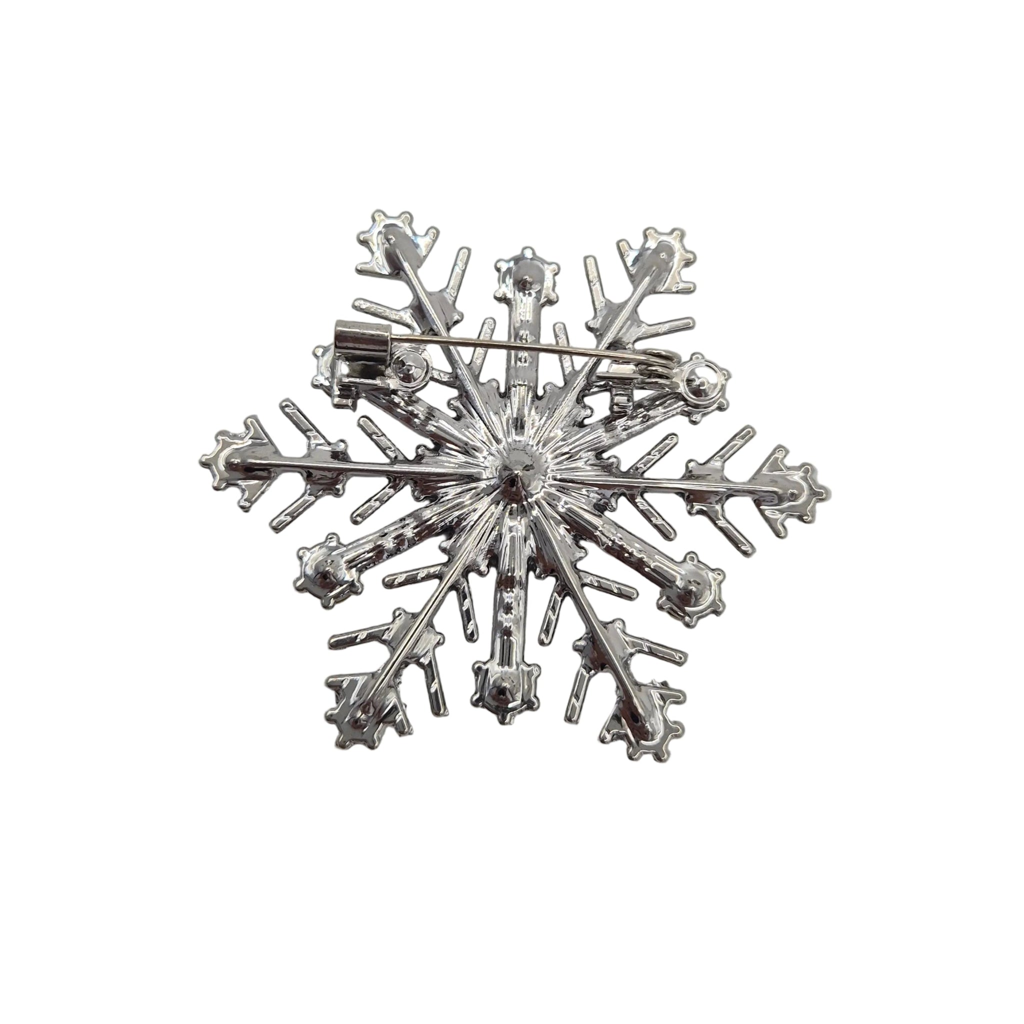 A silver snowflake-shaped brooch with a pin back, displayed on a white background.