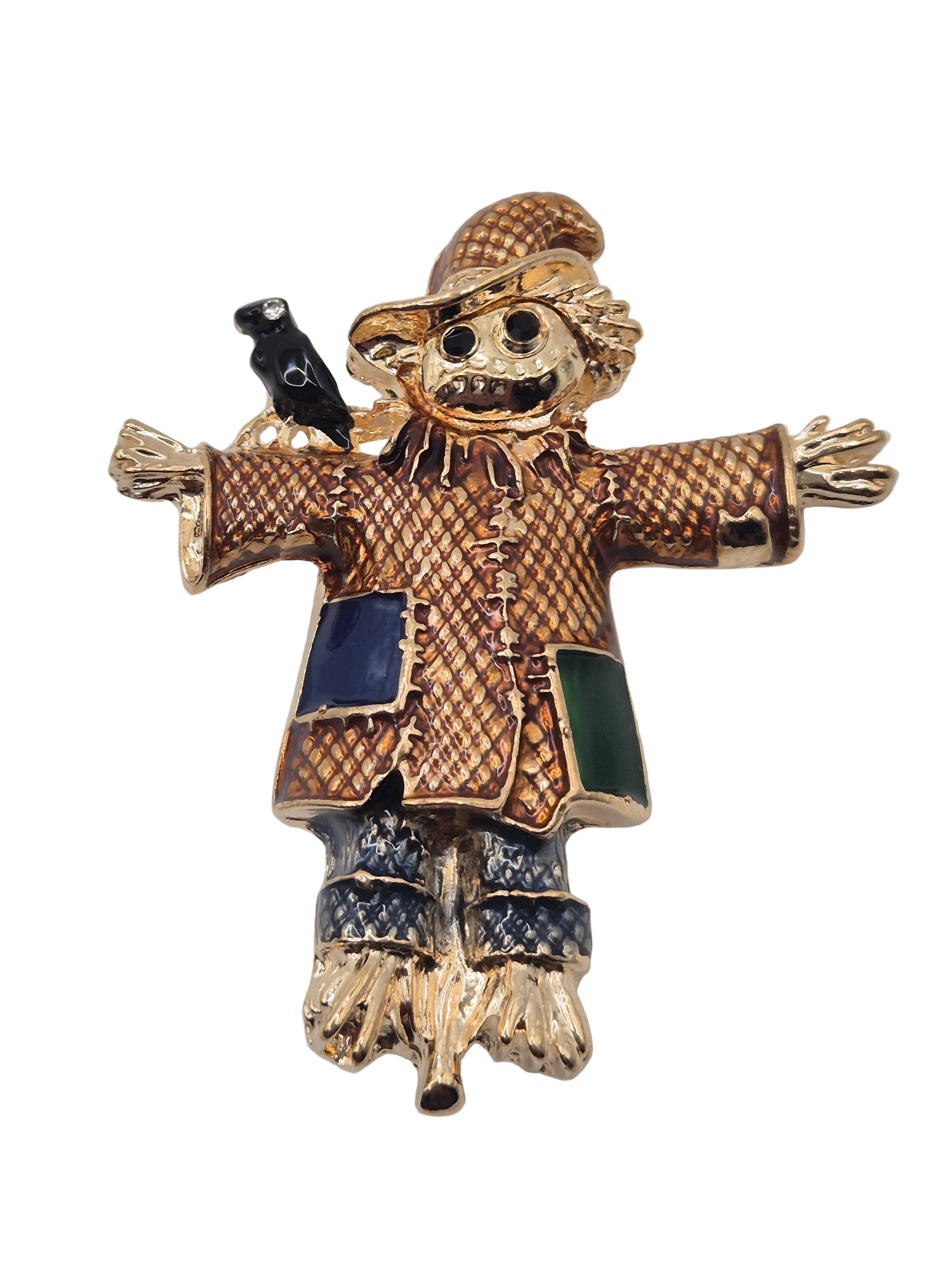 Gold scarecrow brooch with black and blue accents on a white background