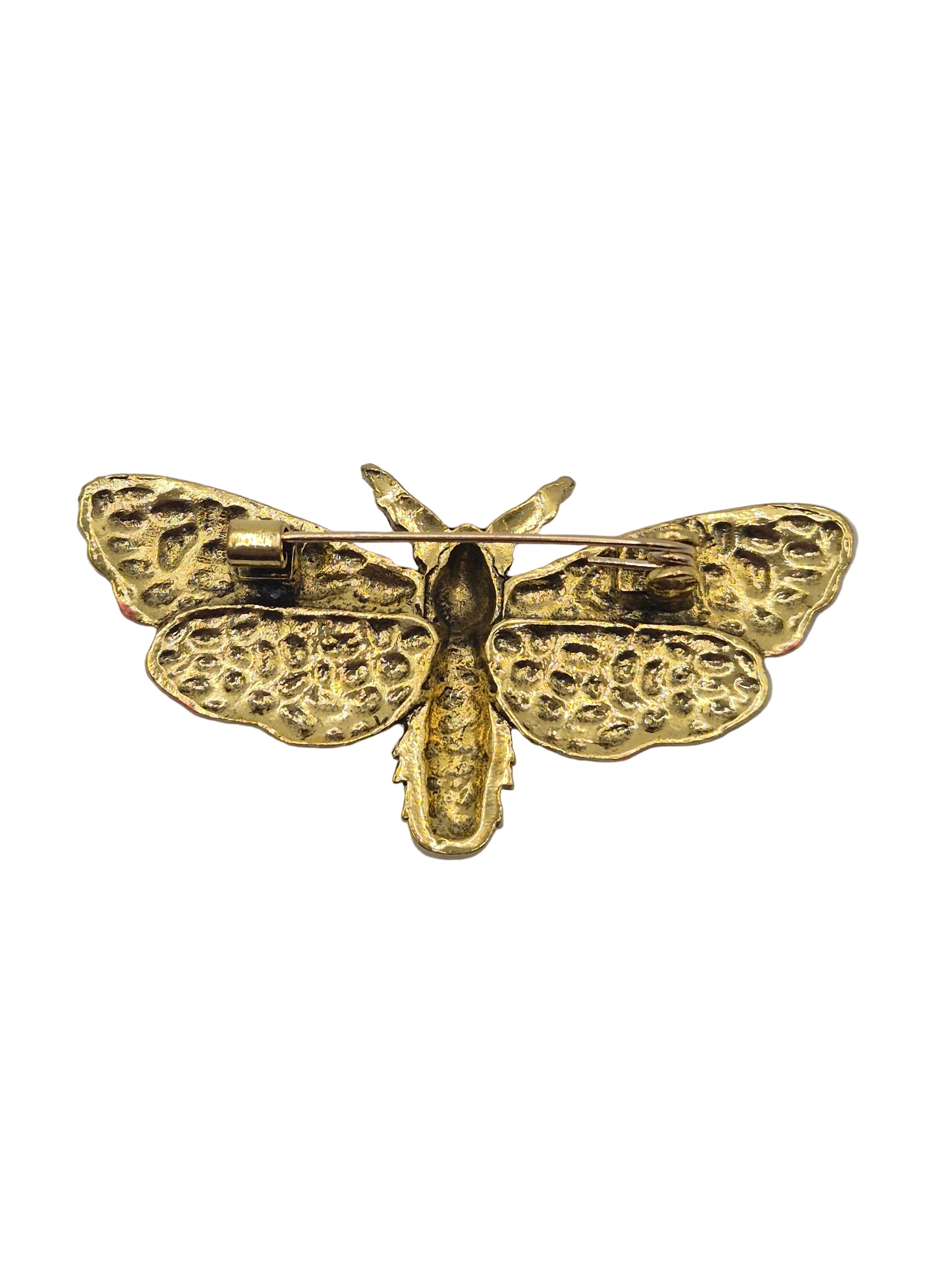 copper moth-shaped brooch on a white background