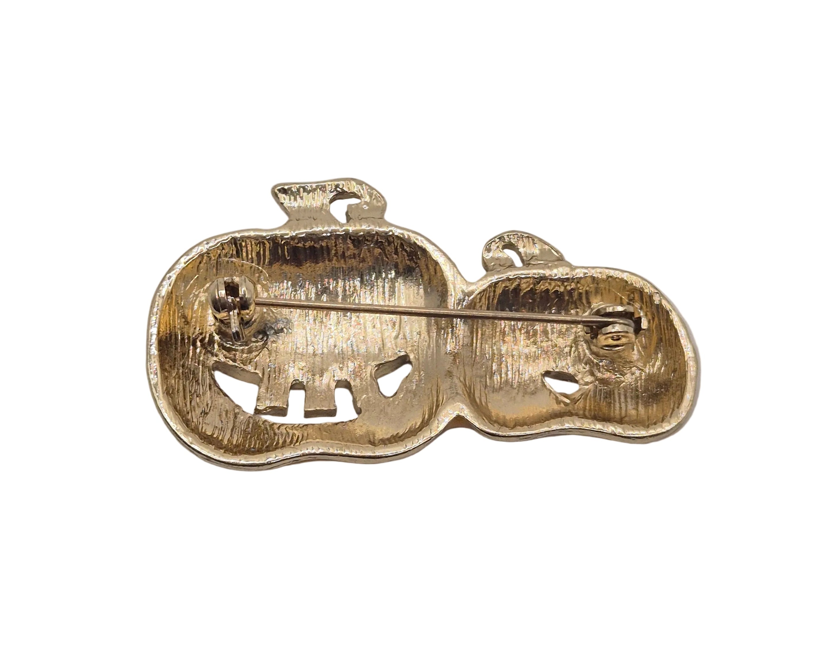 A gold-toned metal pumpkin pin or brooch with a textured, hammered finish, shown from the back on a plain white background.