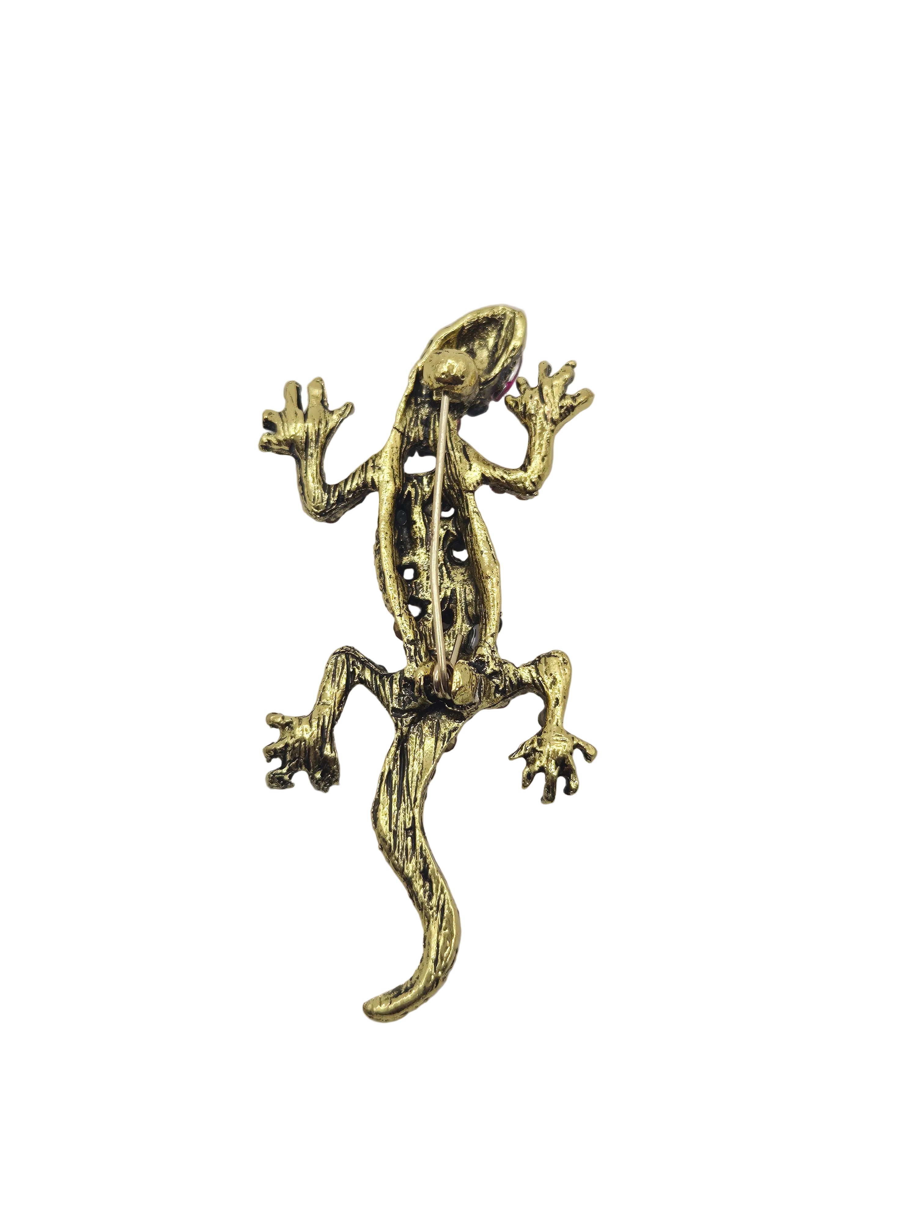 A small lizard or gecko-shaped metallic charm or brooch in an antique gold finish, isolated on a plain white background.