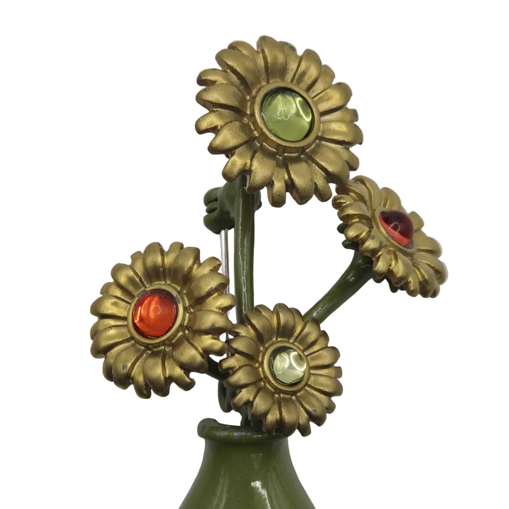 A vintage-style floral brooch featuring four gold-tone flower heads with green, red, and clear faceted center stones, mounted on an olive green stem and vase-like base against a plain white background.