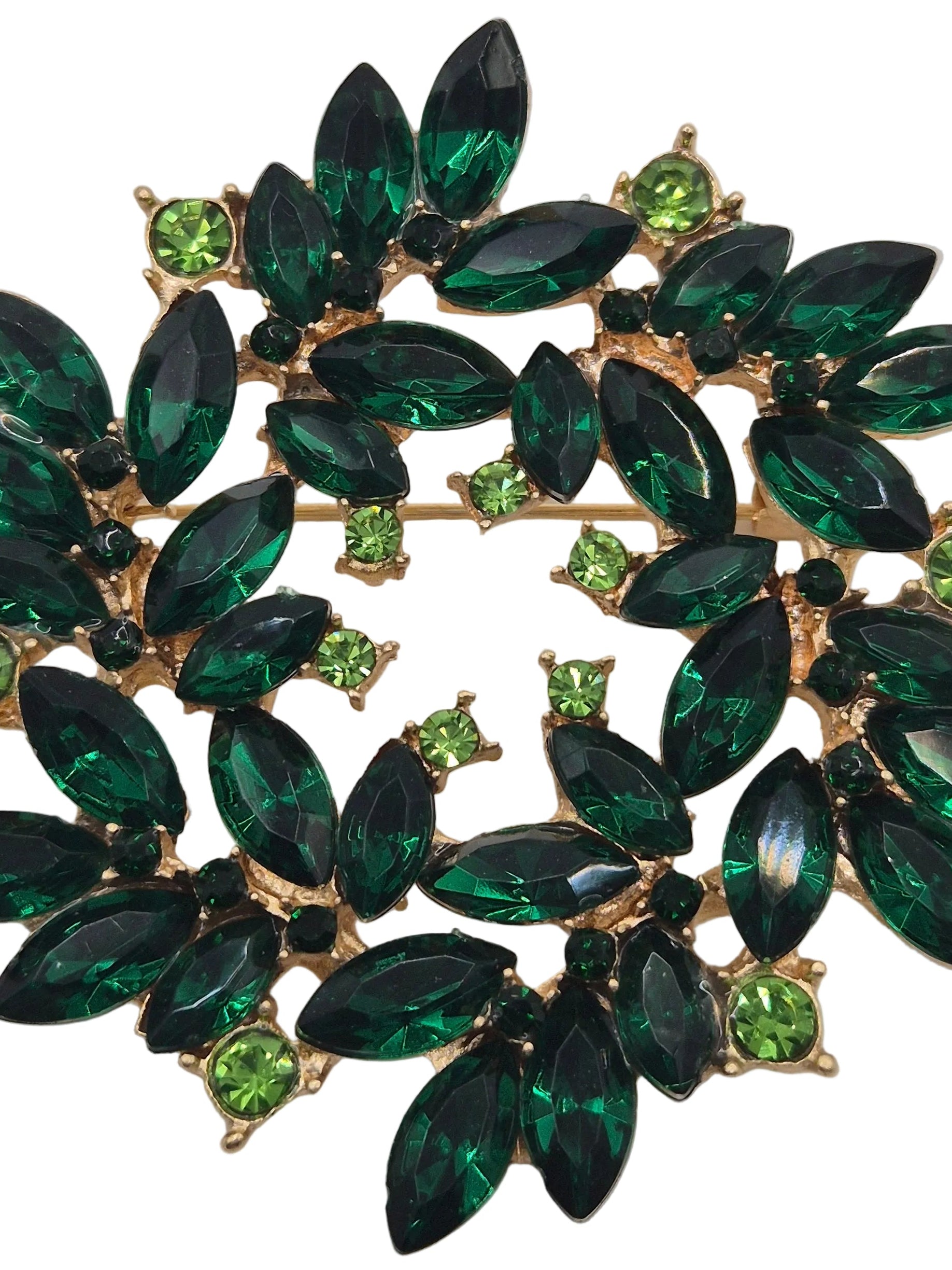 Green gemstone brooch with gold accents on a gray background