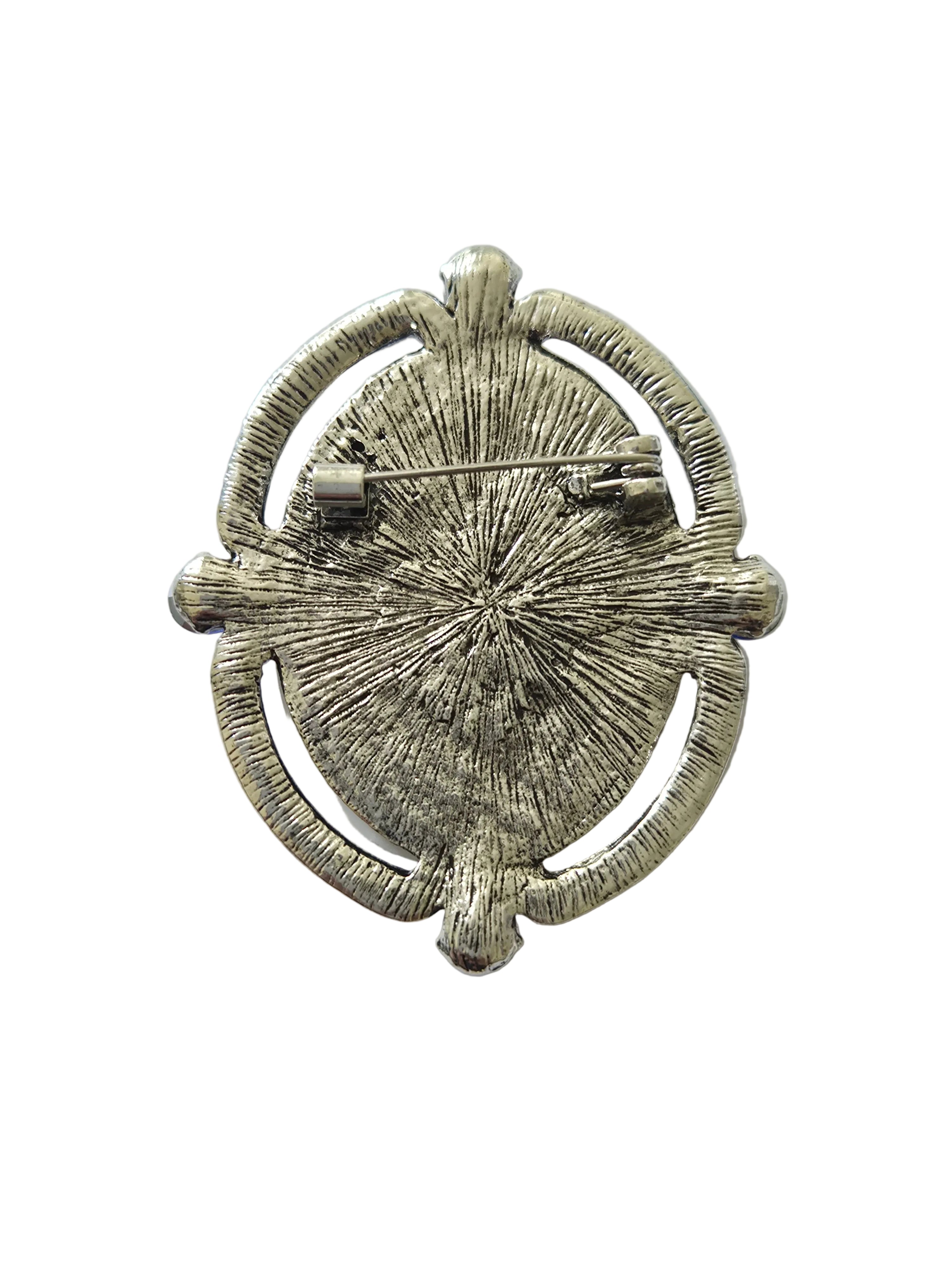 Silver brooch with textured design on a light gray background