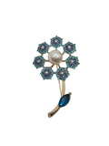 Jewelry brooch with blue gemstones and a pearl on a gray background