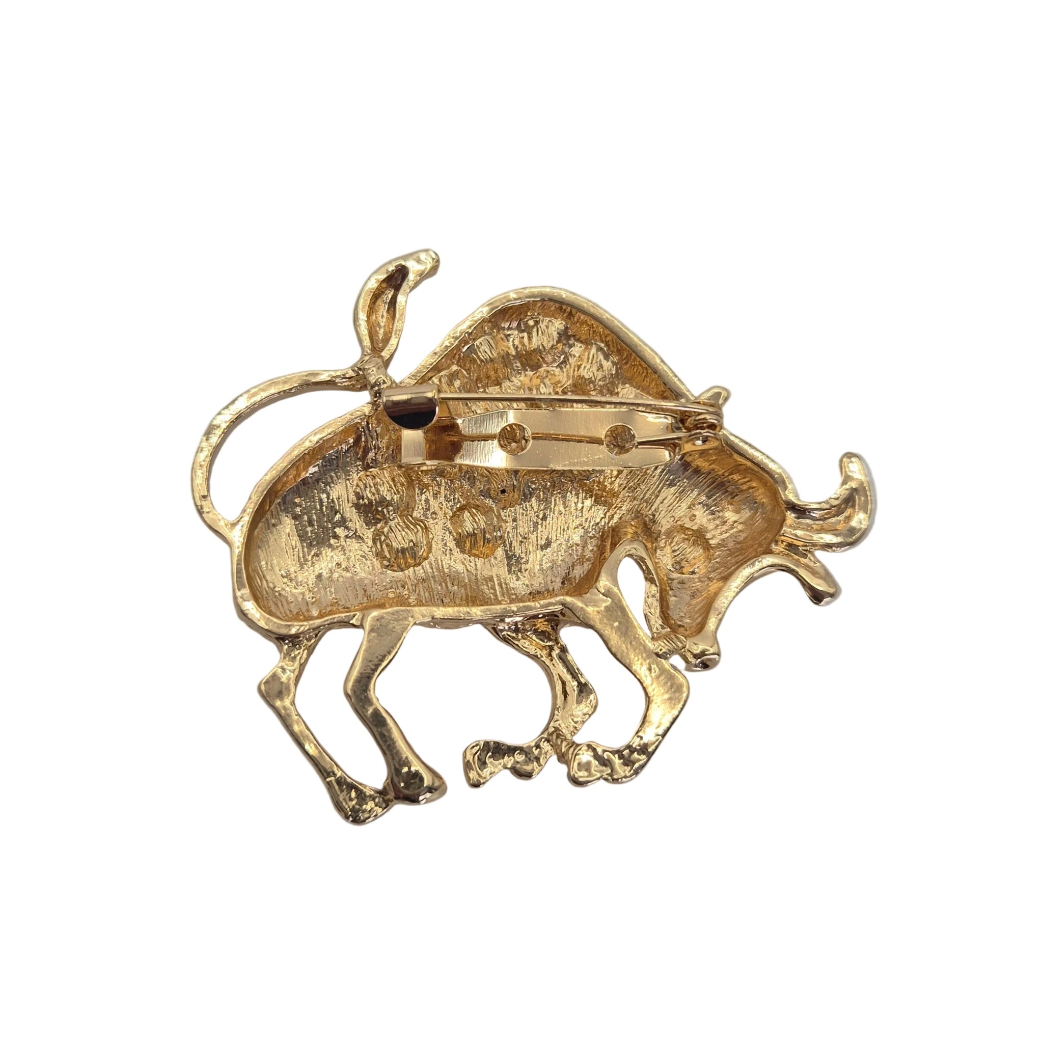 A gold-toned bull-shaped brooch with a textured, hammered finish and a visible pin mechanism on the underside, shown on a plain white background.