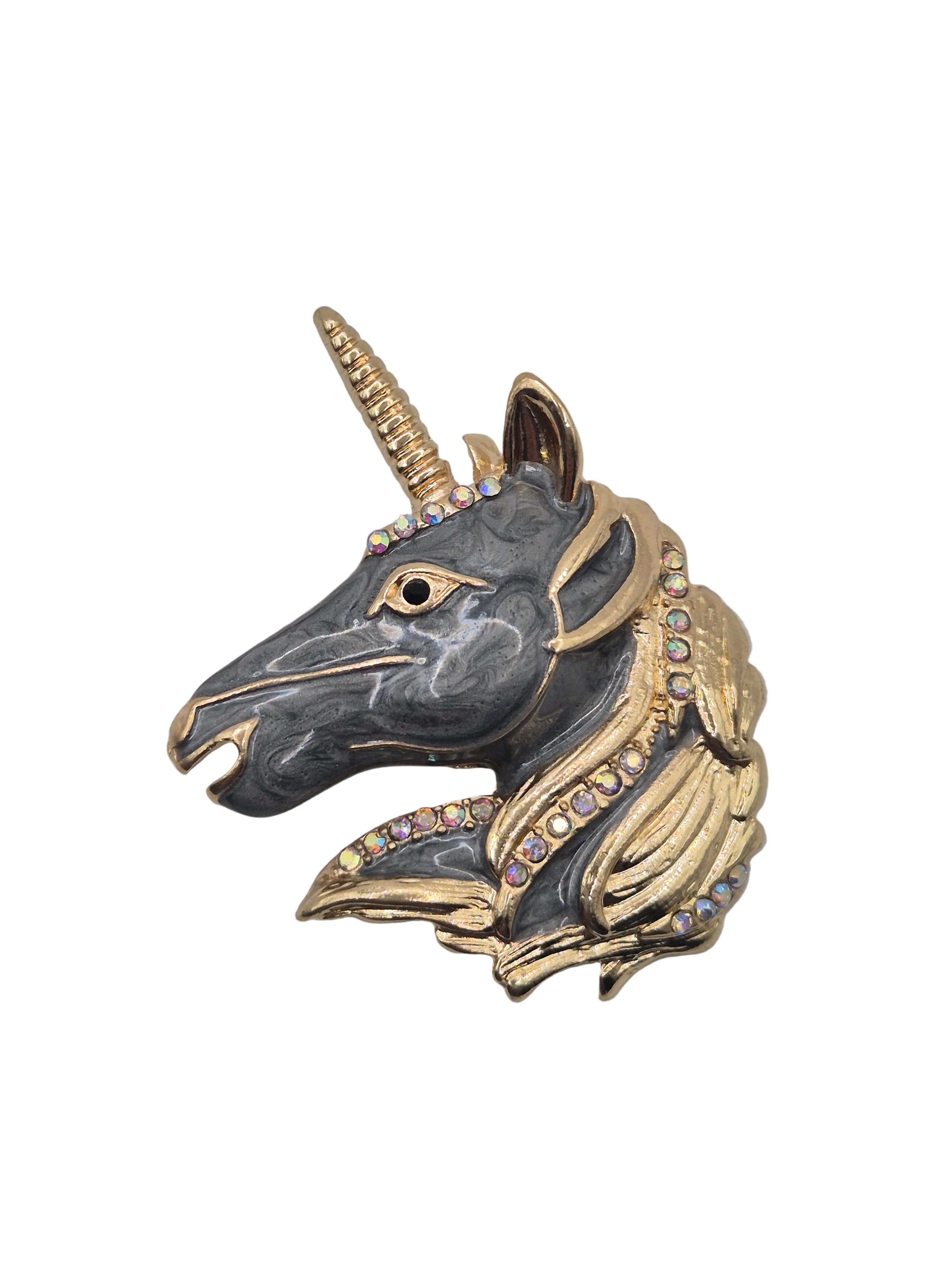 Unicorn head brooch with gold and black details on a white background