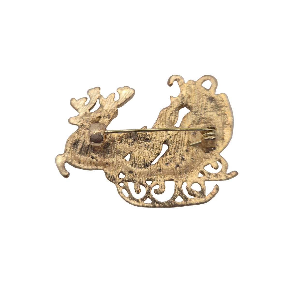 Reverse gold tone side of a Christmas sleigh and reindeer`s brooch, displayed against a plain white background.