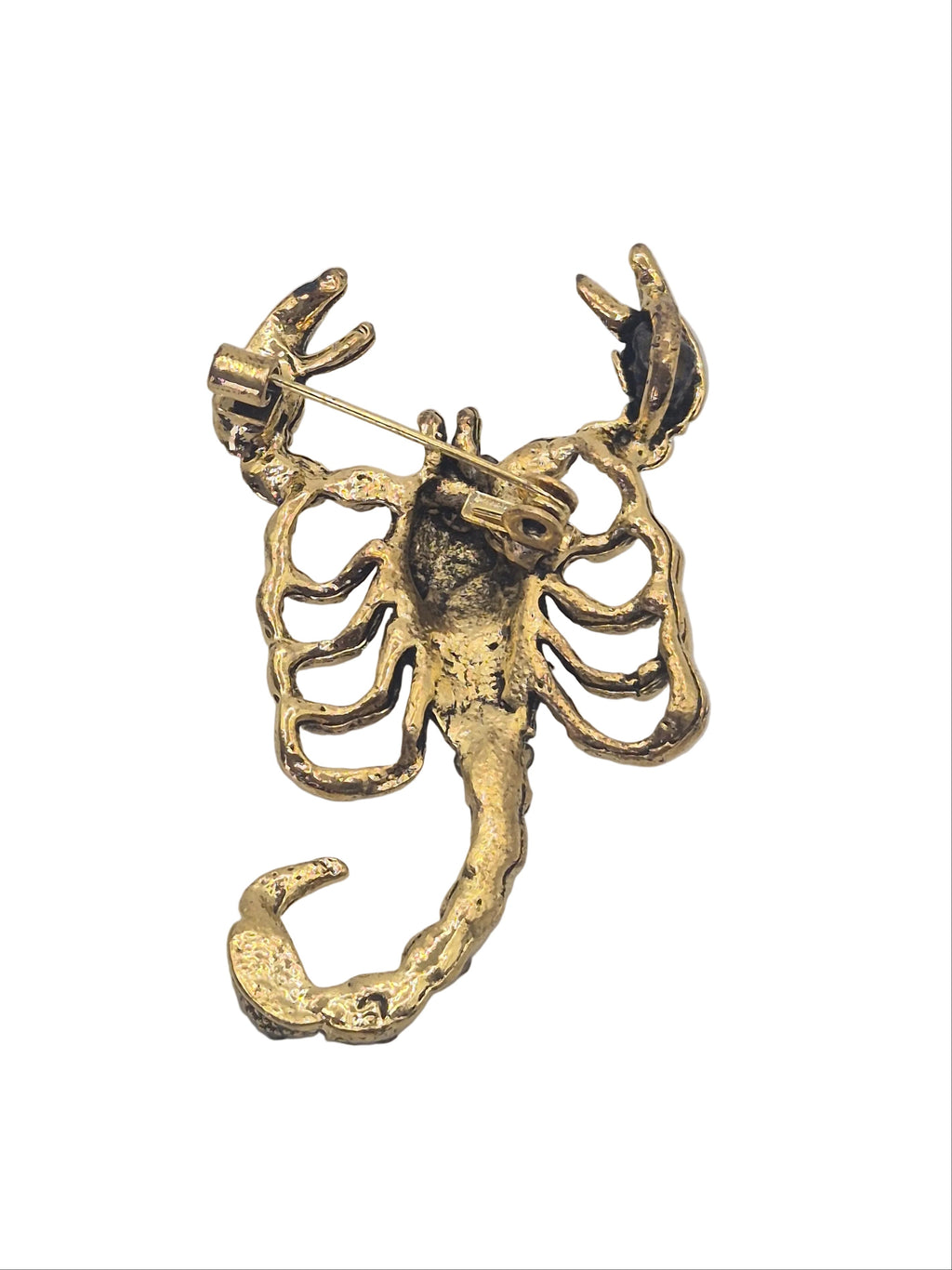 Reverse side of gold metal scorpion brooch on plain white background.