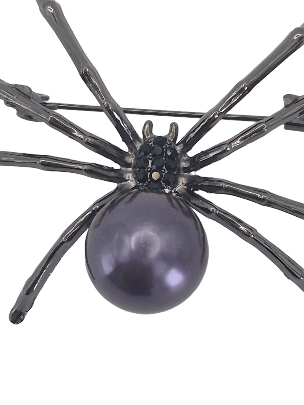 A spider-shaped brooch featuring a dark metallic body and eight textured legs surrounding a large, glossy dark purple pearl, set against a plain white background.