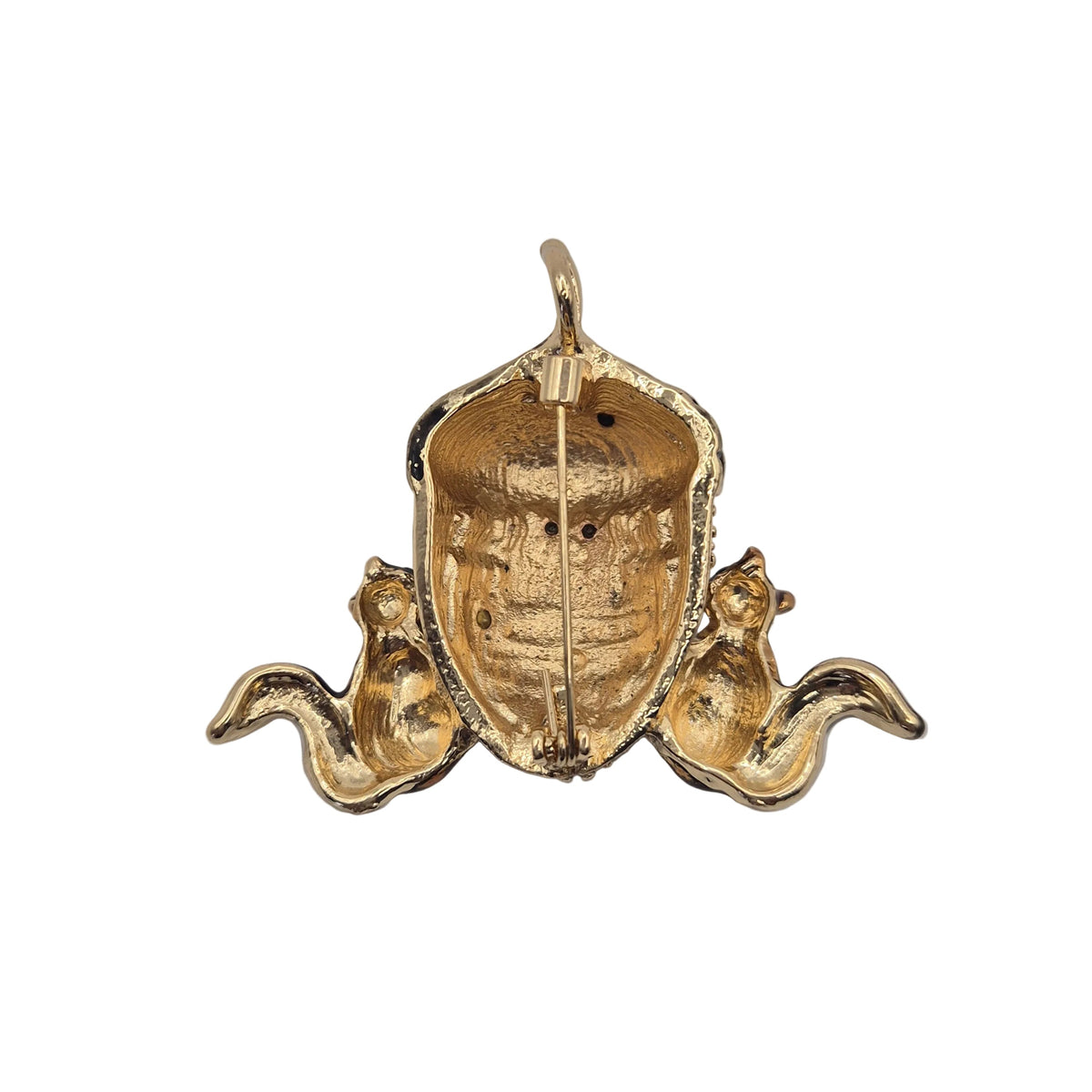 A vintage-style gold tone brooch or pendant featuring two small squirrels flanking a large acorn, shown from reverse side set against a plain white background.