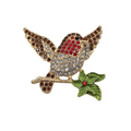 A gold-tone robin bird brooch embellished with red, brown, and clear rhinestones, perched on a green leafy branch with a small red center detail, shown on a plain white background.
