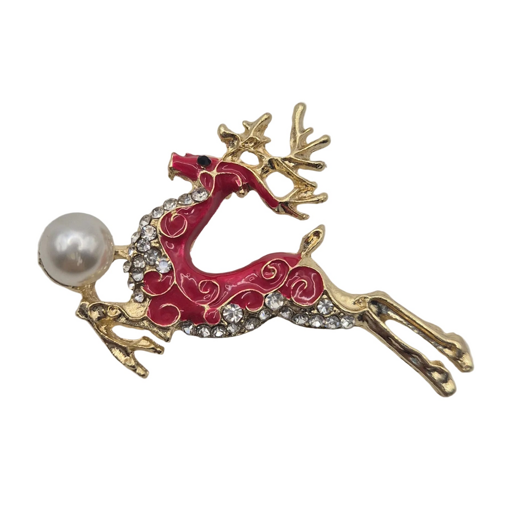 A festive Christmas reindeer brooch featuring a gold-tone metal body, vibrant red enamel swirls, a white faux pearl, and clear rhinestones, set against a plain white background.