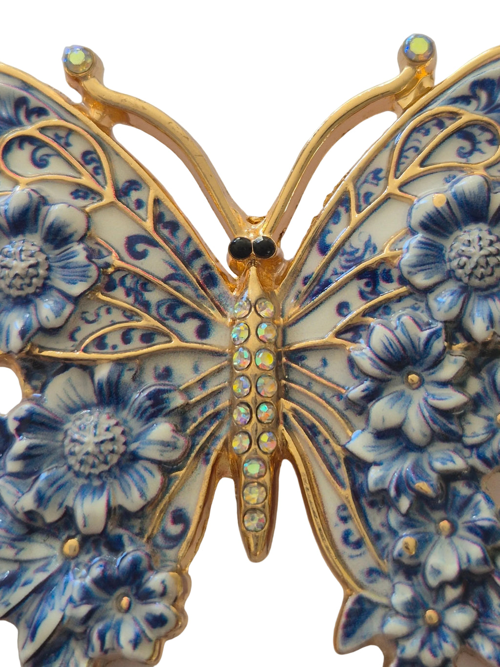 Decorative butterfly brooch with floral patterns and gold accents on a white background