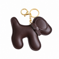 A dark brown leather dog-shaped keychain  bag charm with gold-tone metal hardware, shown on a plain white background.
