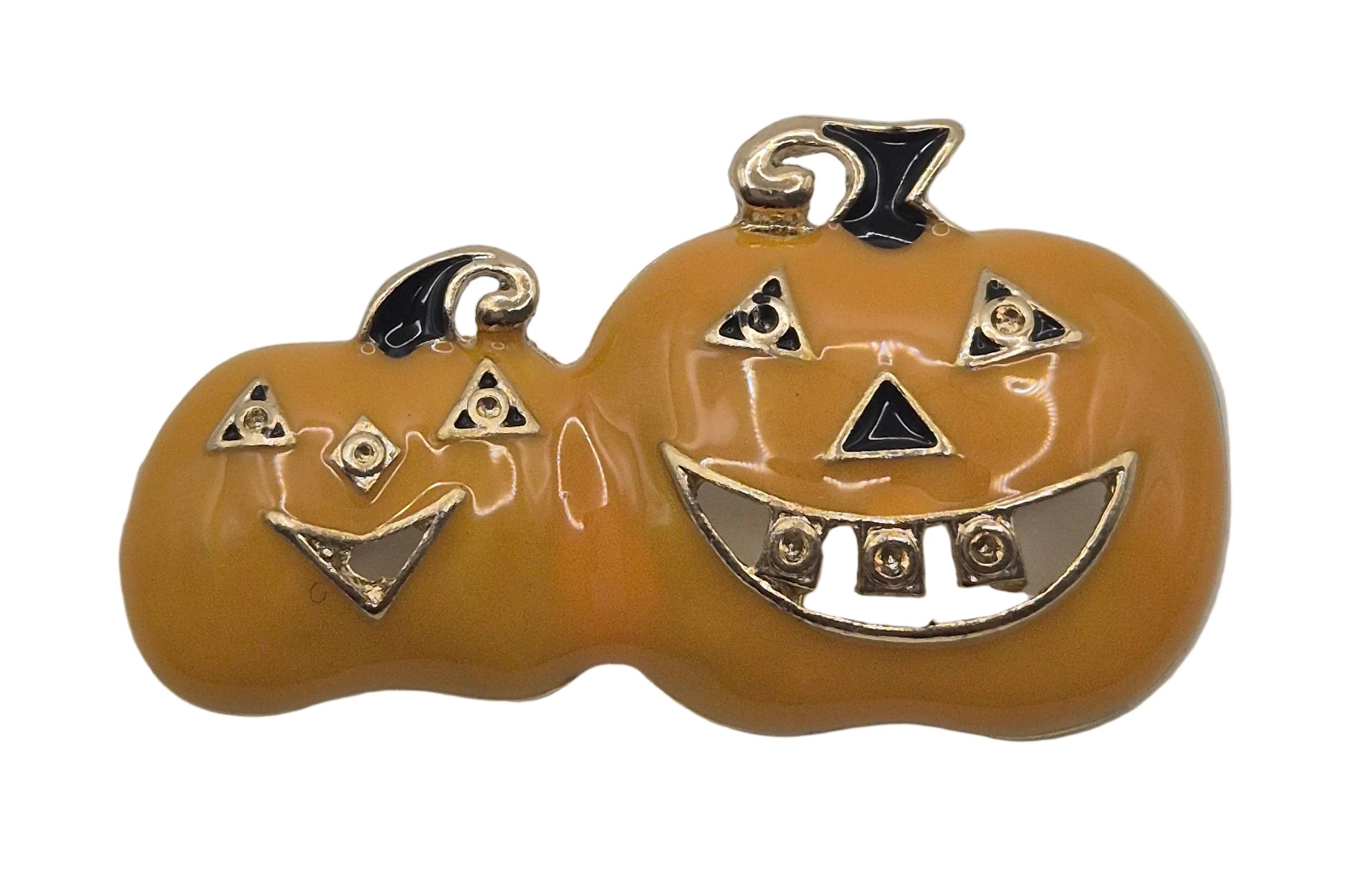 A double pumpkin Halloween brooch featuring a smaller jack-o'-lantern on the left and a larger carved pumpkin on the right, both in a glossy orange enamel with gold-tone metal outlines and black enamel accents.