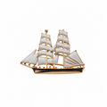 A gold-plated metal ship brooch with white enamel sails and small red accents along the hull, shown on a plain white background.