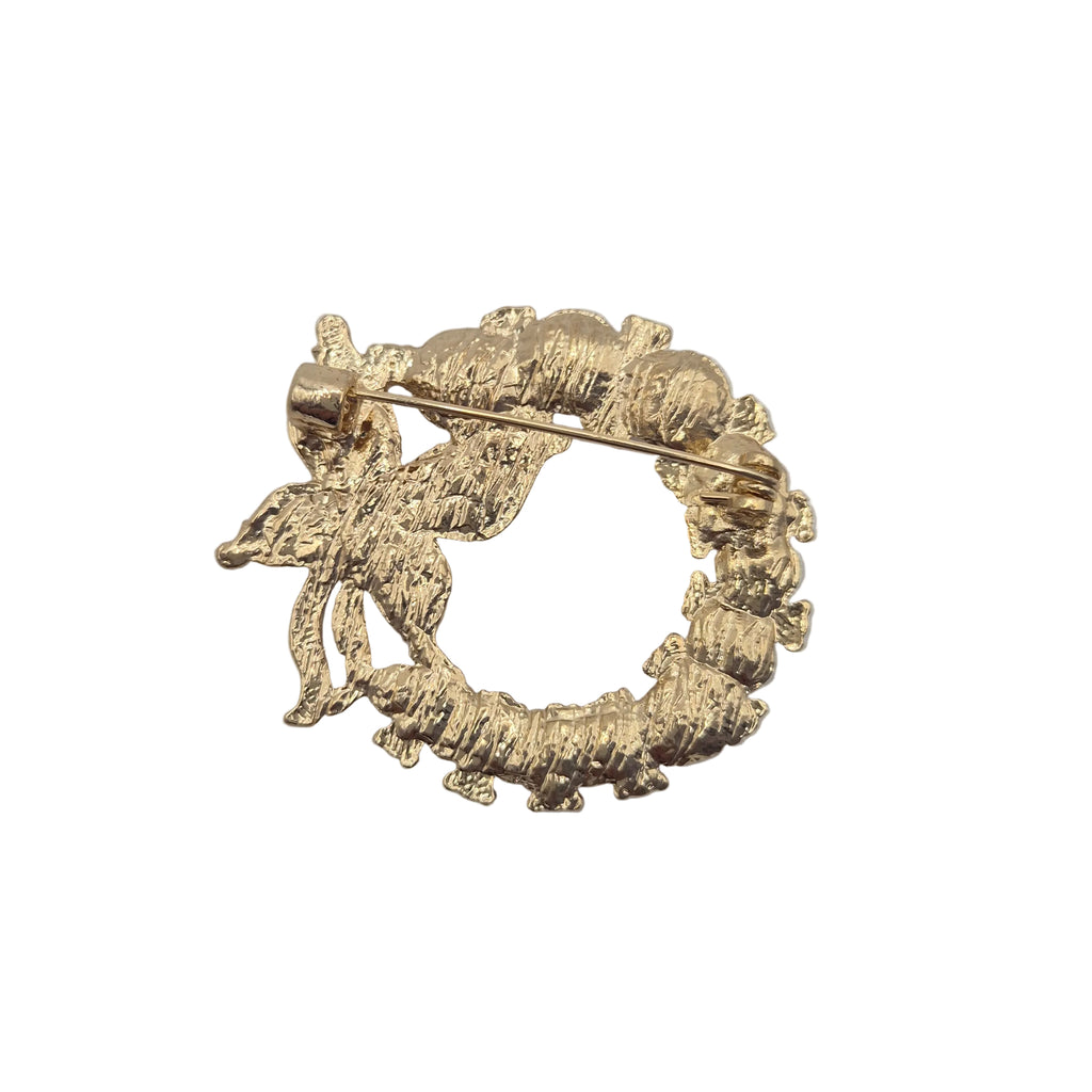 A textured gold-tone circular brooch with a pin fastener, photographed on a white background.