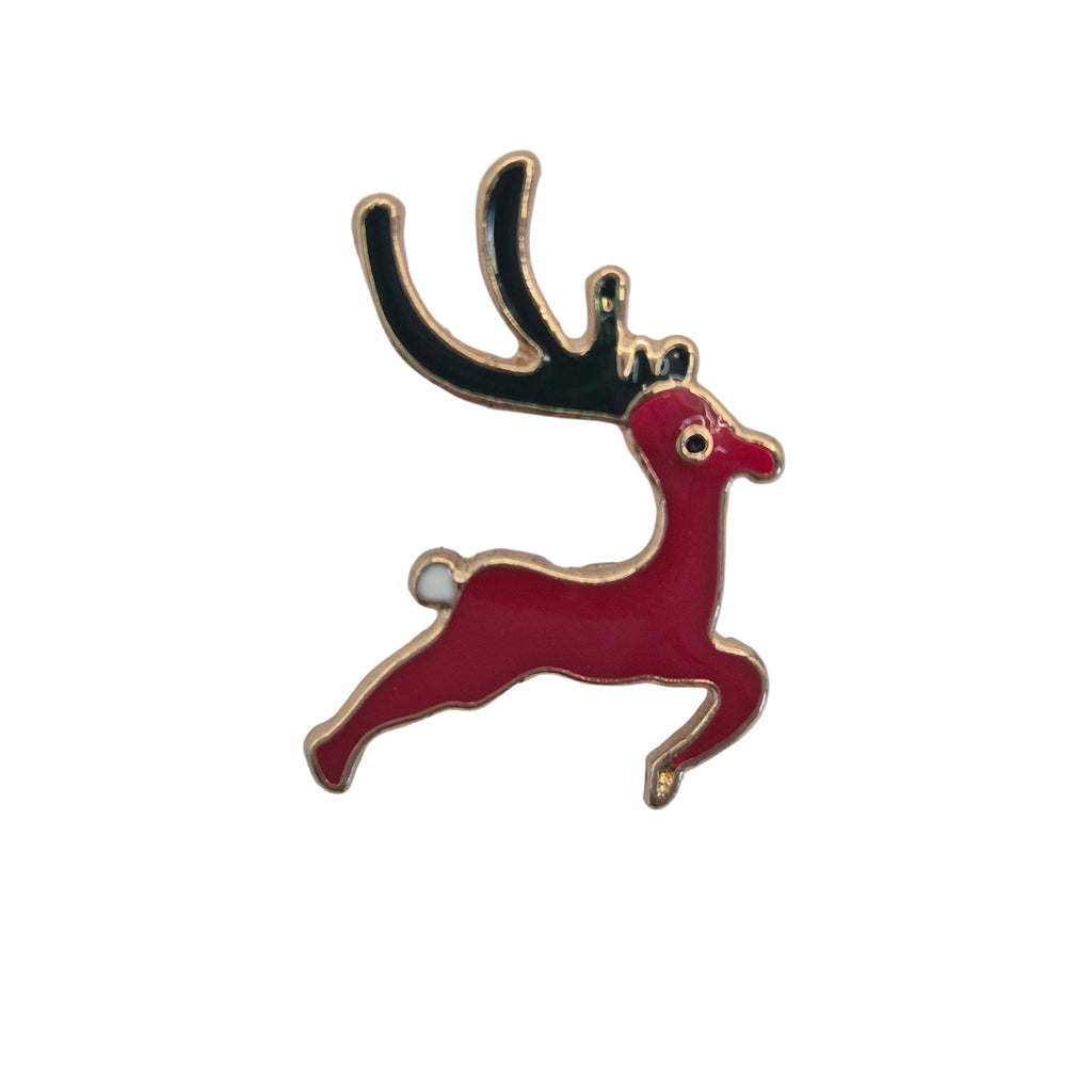 A festive enamel lapel pin shaped like a leaping red reindeer with black antlers and gold-tone metal outlines, isolated on a white background.