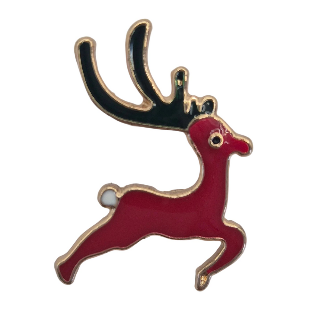 A festive enamel lapel pin shaped like a leaping red deer with black antlers and gold trim, shown on a plain white background.