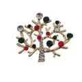 A gold-toned tree-shaped brooch decorated with faceted rhinestones in red, dark green and clear, set against a plain white background.